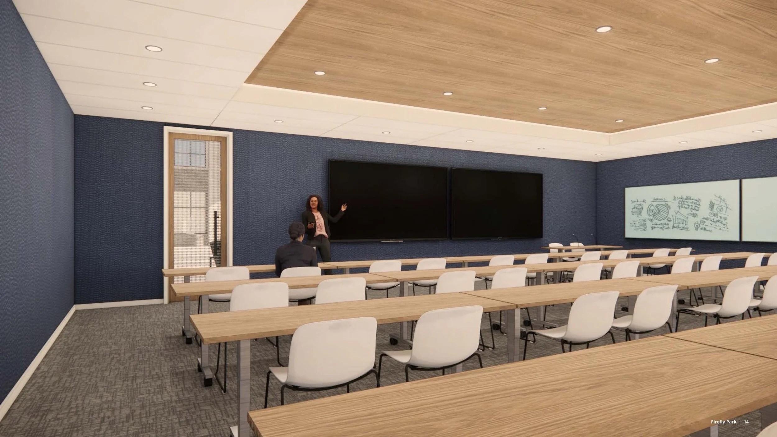 A large training room with rows of long tables with chairs, blue walls, and a large screen on the wall