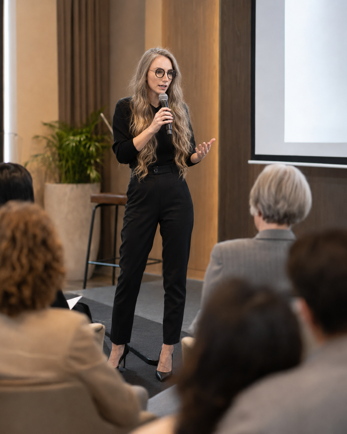 Martina Kikic speaking with a microphone to a seated corporate audience on executive presence