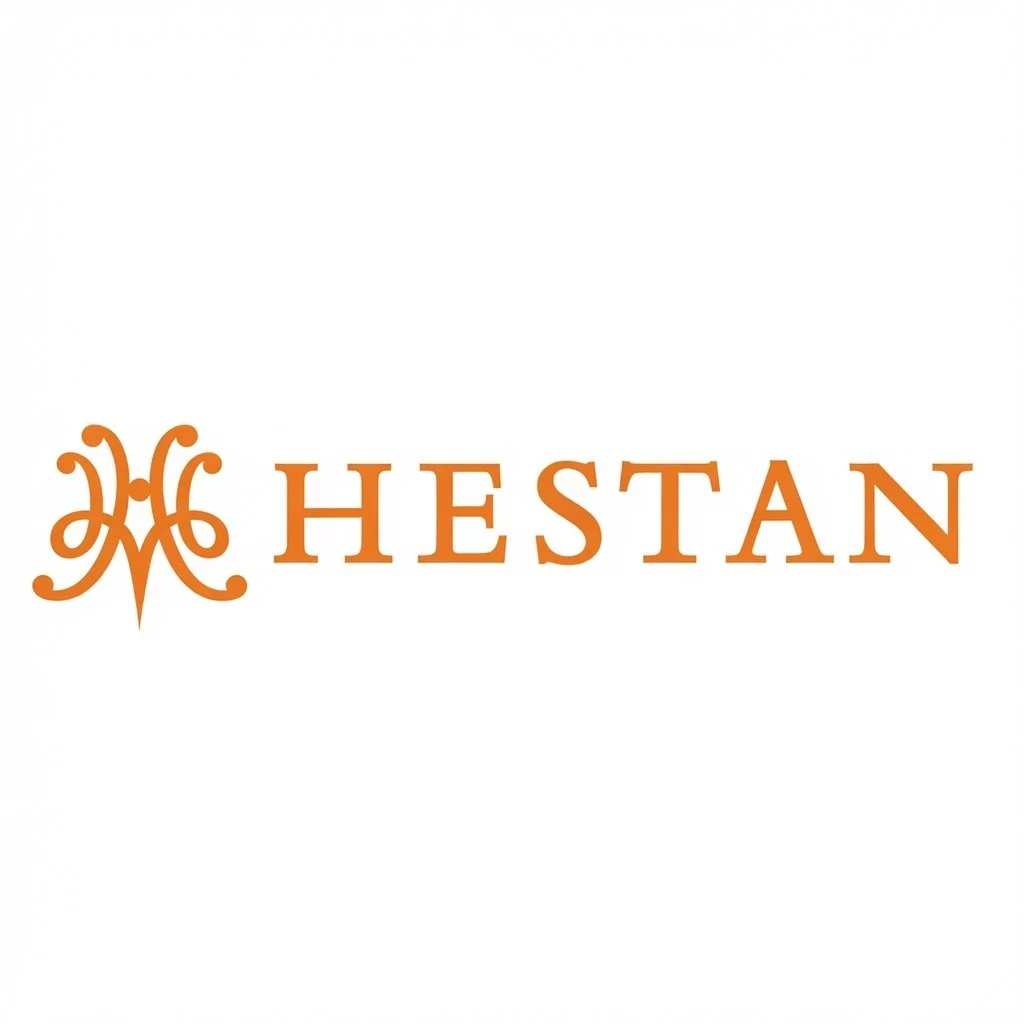 Hestan logo with ornamental emblem and the word 'HESTAN' in orange capital letters on a white background.