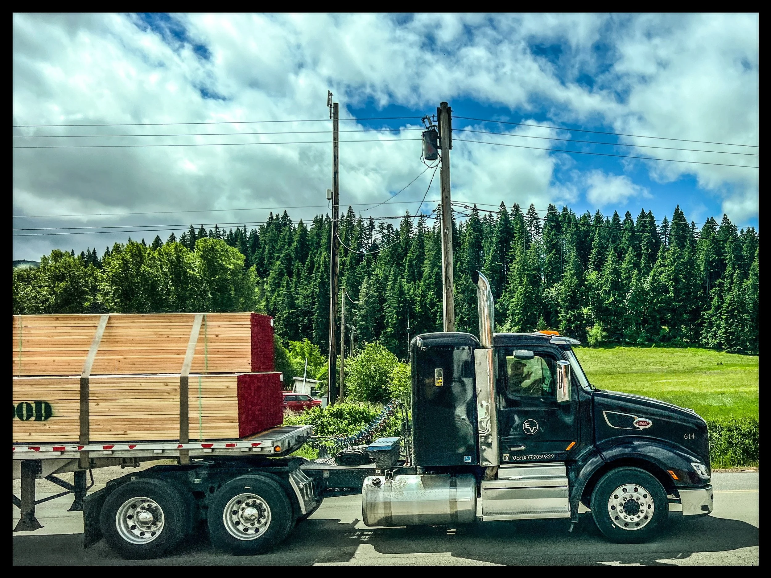Flatbed Owner Operator with black truck hauling load of lumber