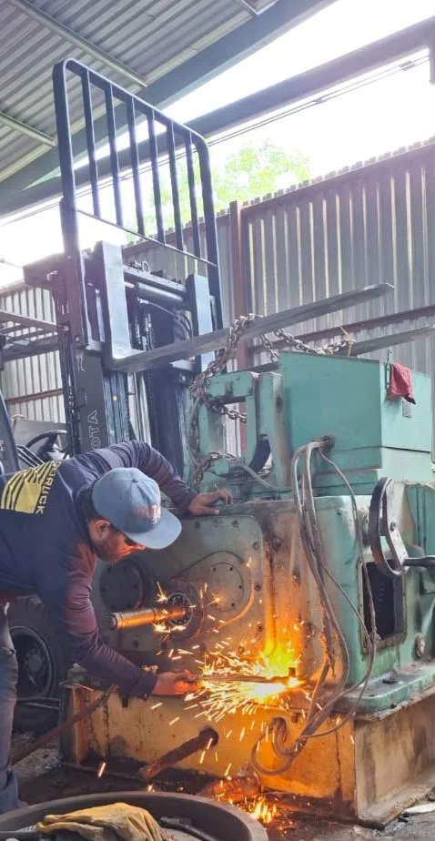 hombre utilizando un soplete para cortar maquinaria metálica para reciclaje
