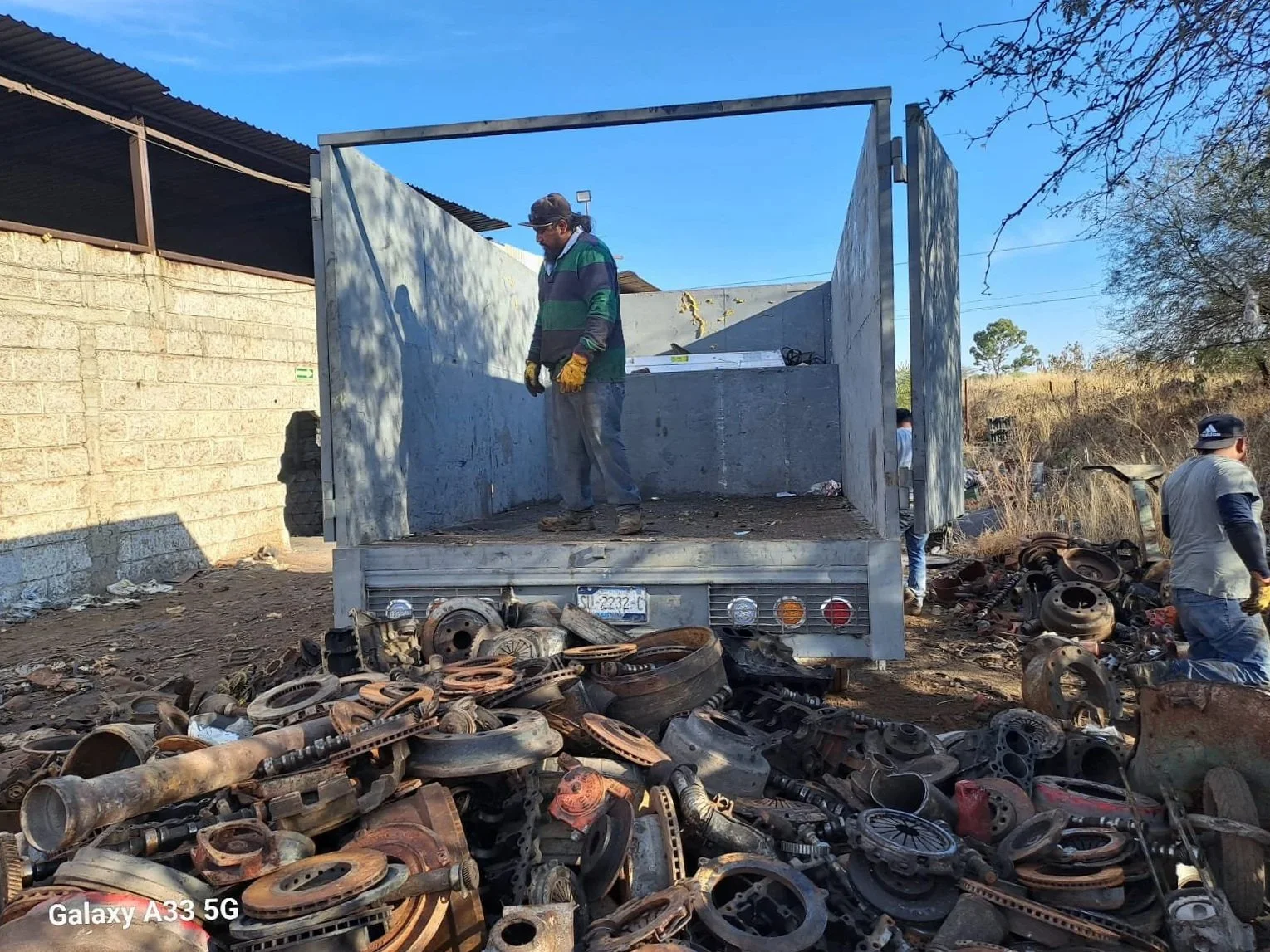 camioneta con contenedor gris recolectando piezas metálicas de autopartes para reciclaje