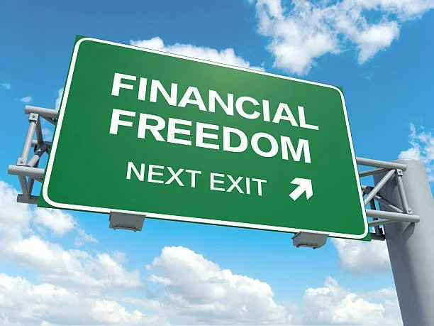 Green highway sign reading 'Financial Freedom Next Exit' against a sky background.