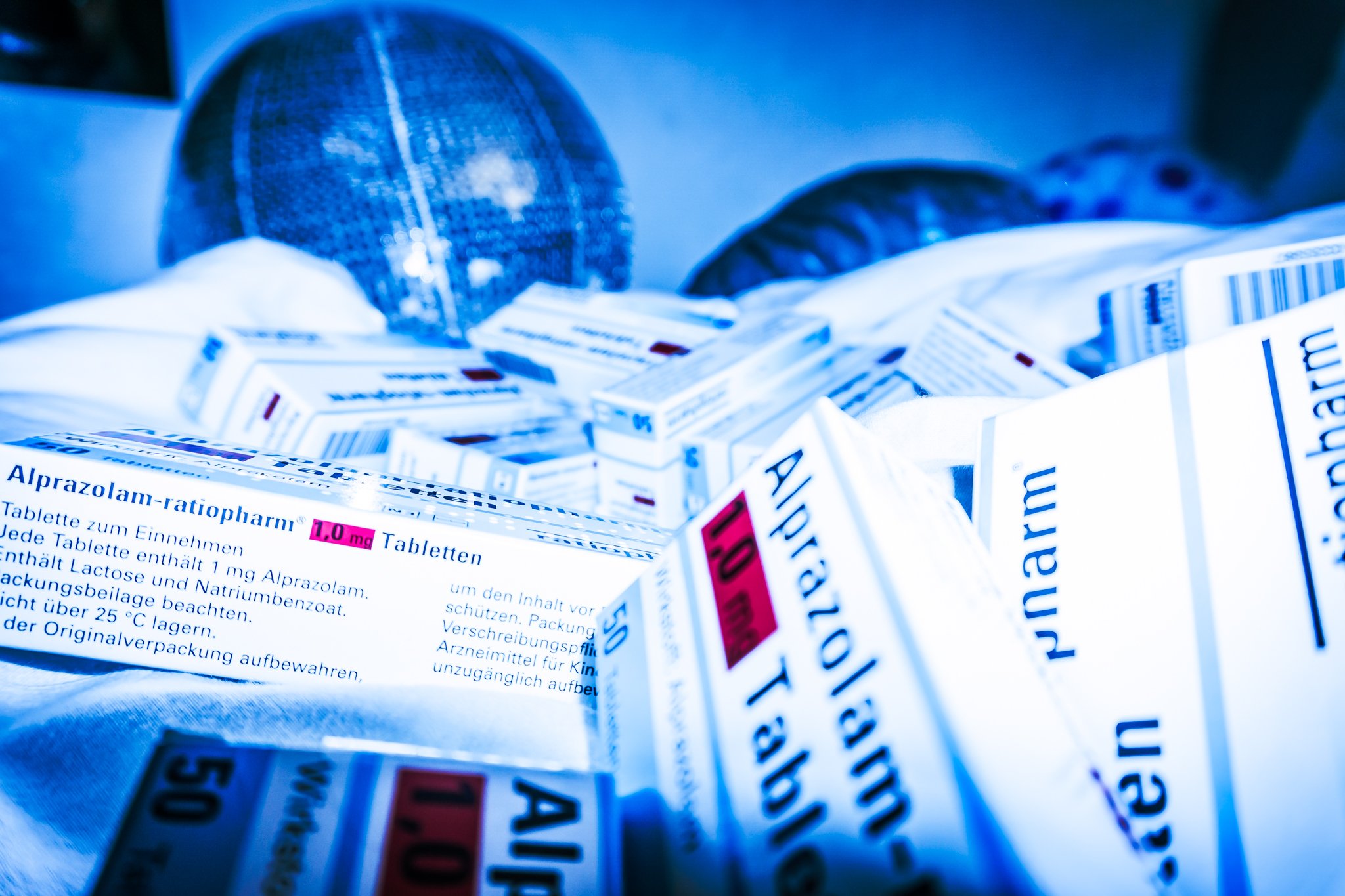 Mehrere Boxen mit Medikamenten, darunter ein Medikament namens 'Alprazolam-ratiopharm', auf einer blauen Oberfläche.