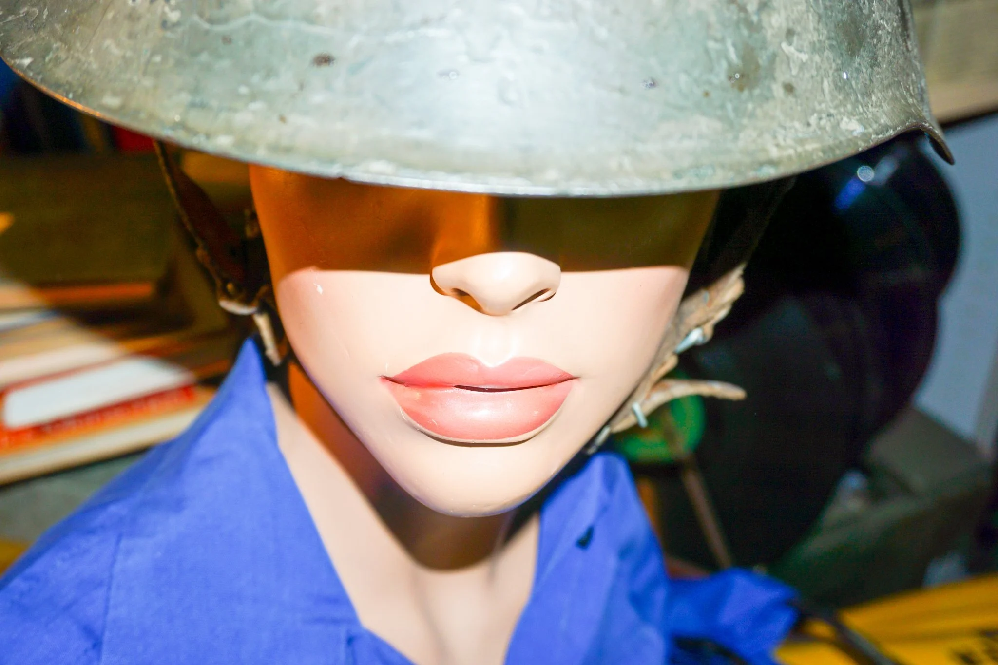 Puppe mit militärischem Helm, blauer Kleidung, pinker Lippen und geschlossener Miene.