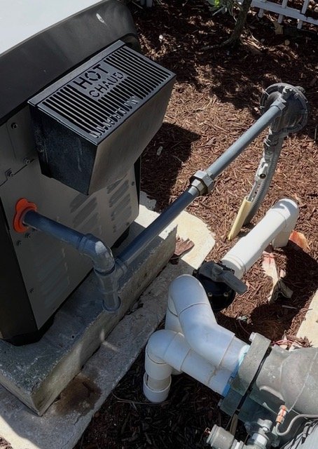 Outdoor pool heater gas plumbing with pipes and a control panel labeled "HOT TUB".