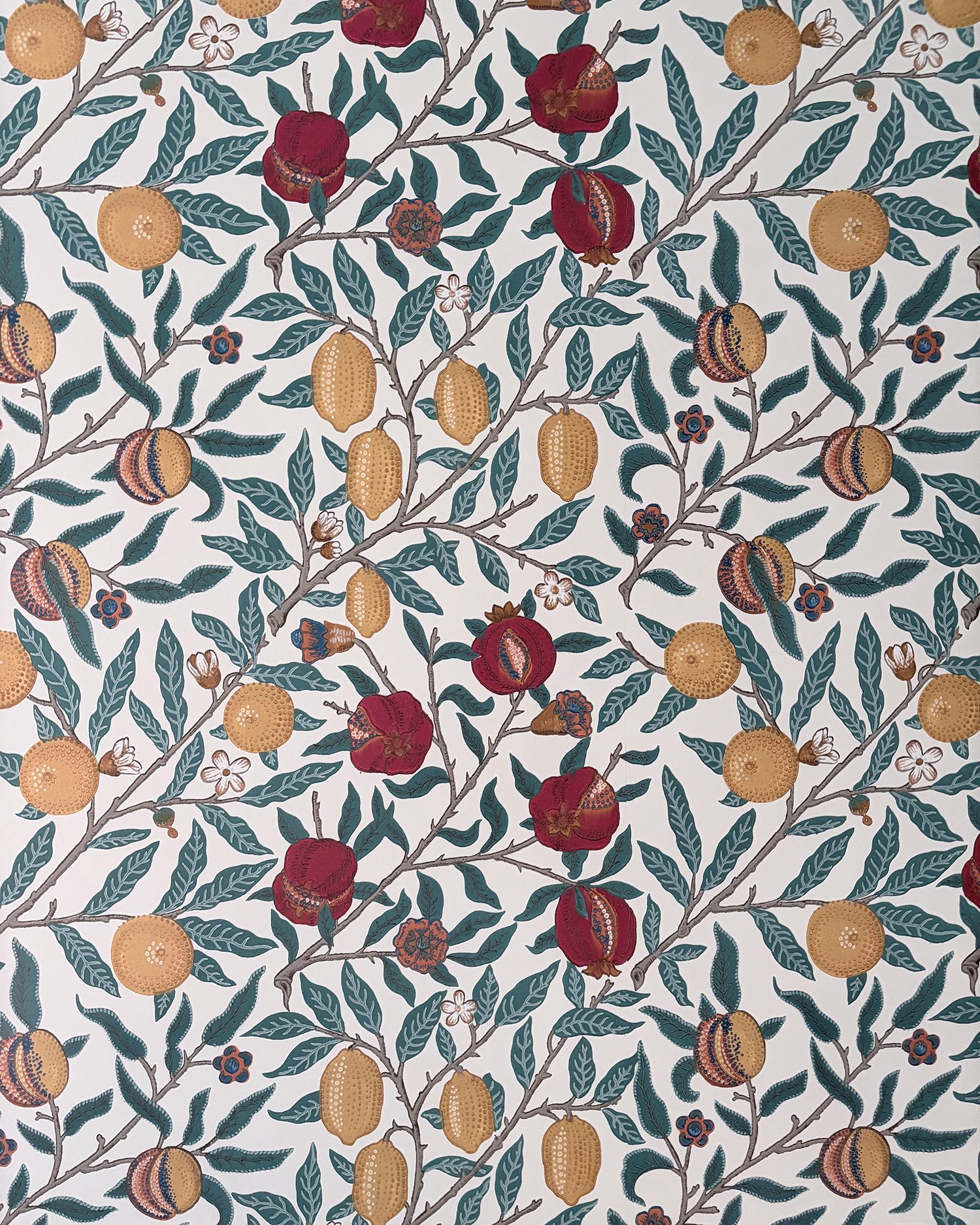 Pattern of pomegranate fruit, branches, leaves, and small flowers on a white background.