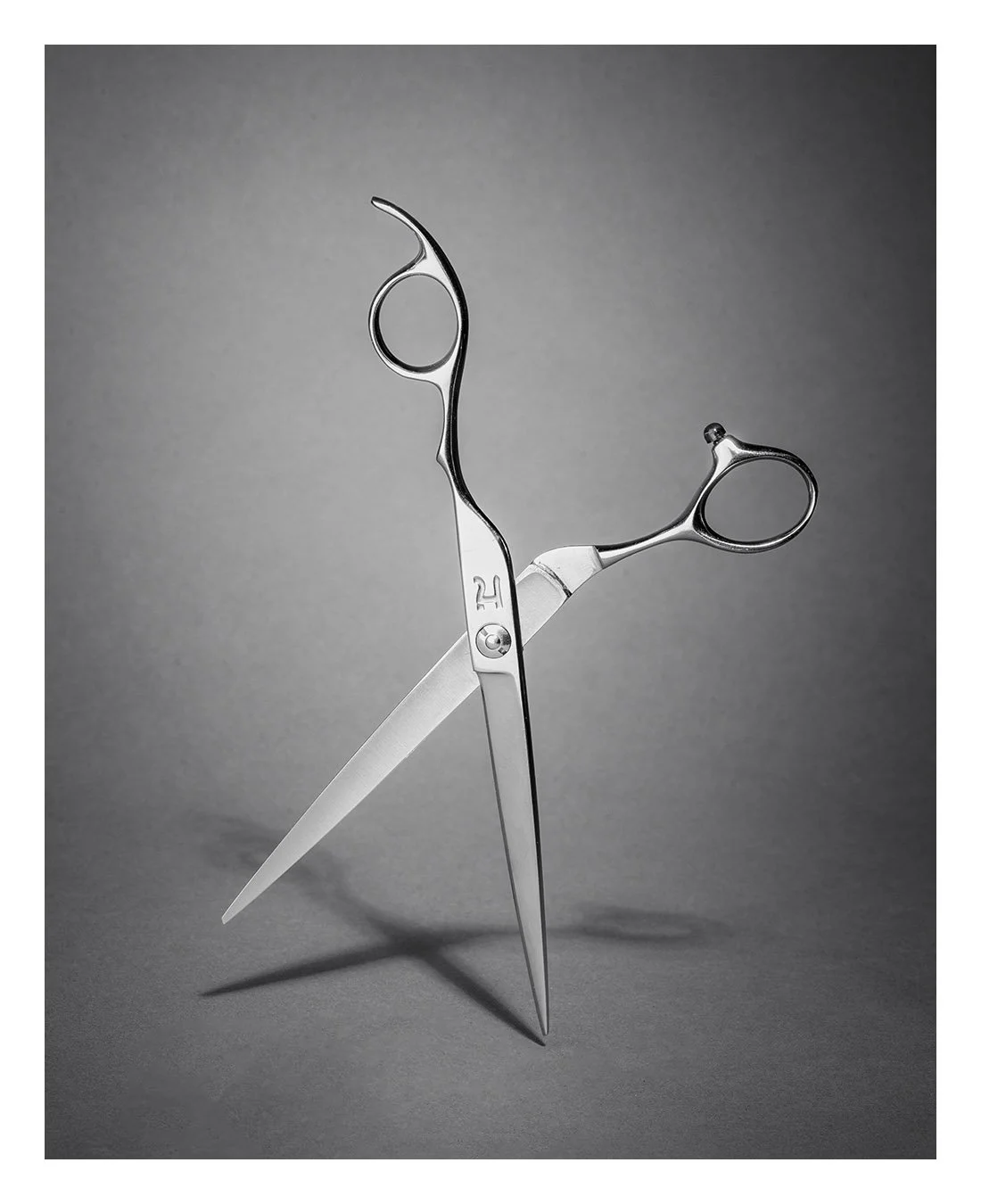 haircutting instruments, arranged to form a balanced, sculptural figure against a gray background.
