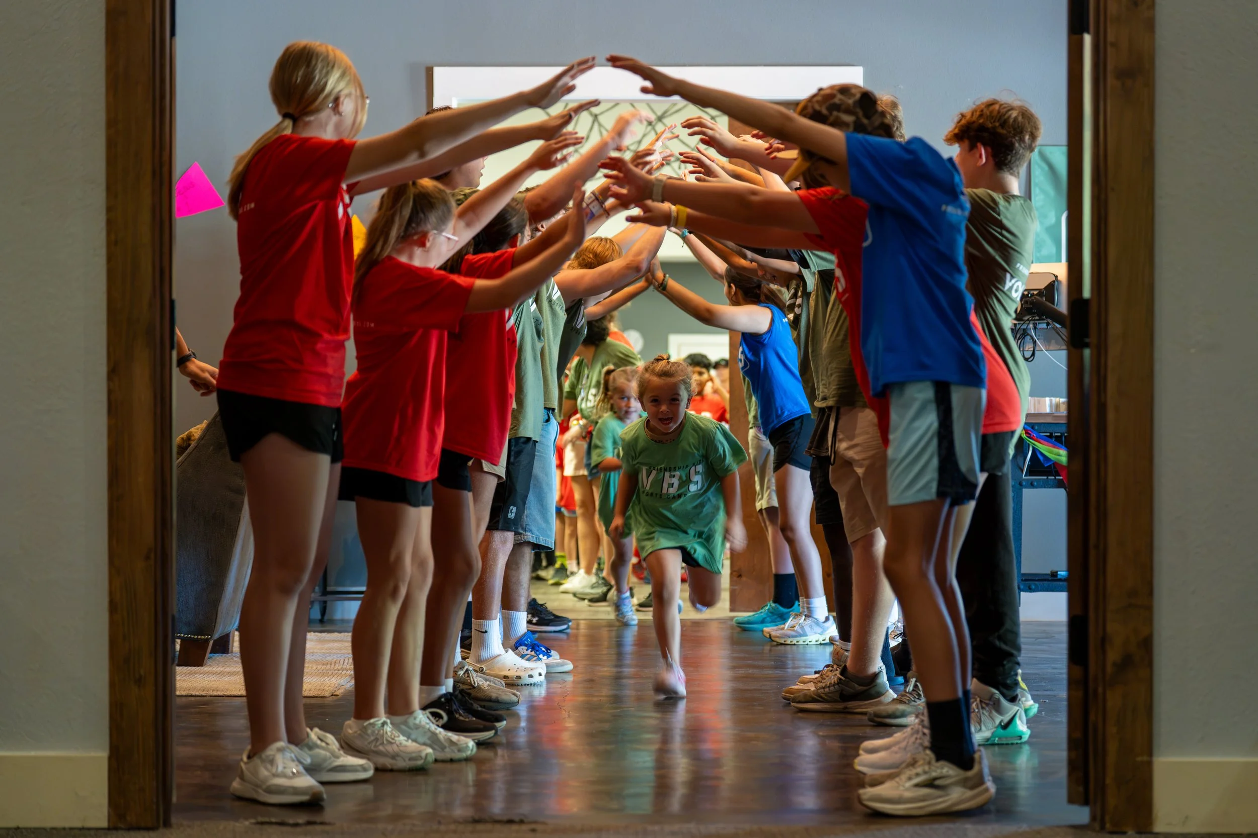 Children walking through a hallway forming a tunnel with their hands.