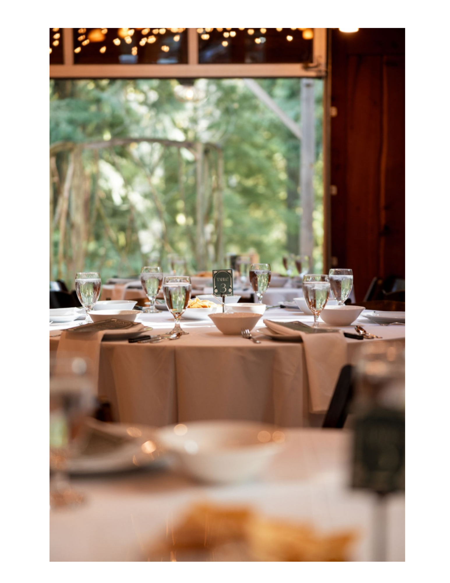 multiple tables set for a meal in the center of the image with a table number decoration