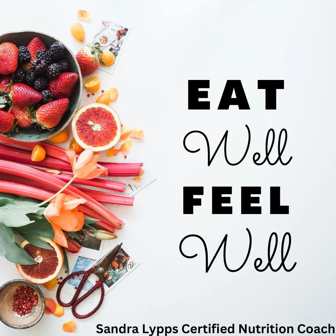 Flat lay of fresh berries, citrus fruits, rhubarb stalks, and flowers next to a quote 'Eat Well Feel Well' by Sandra Lypps with a white background.