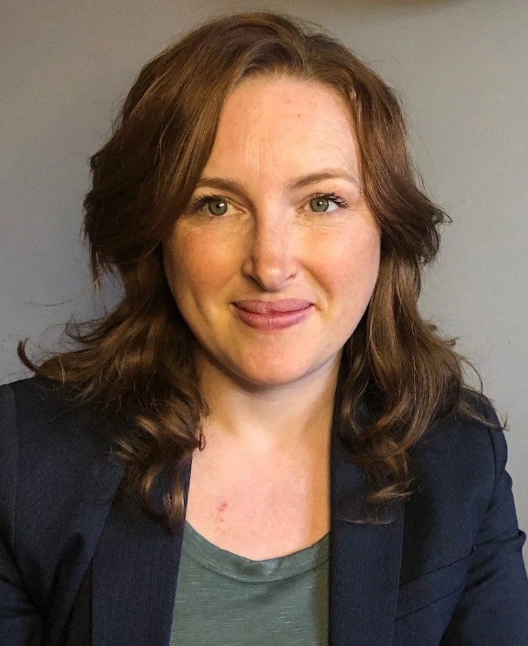 Dr. Melanie Barham is smiling slightly in front of a plain gray background.
