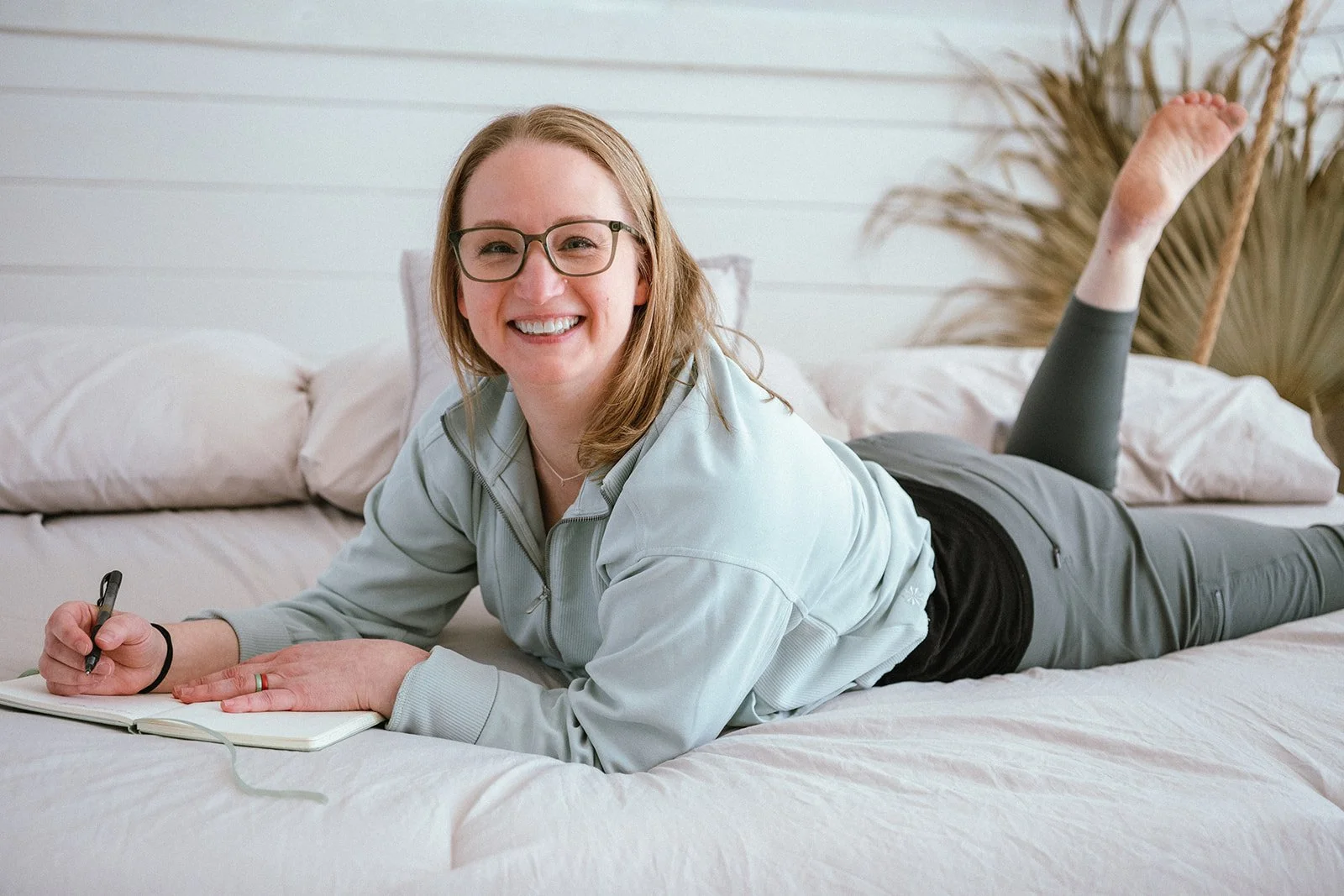 dr amanda townsend smiling on a bed during a brand shoot for root and rise consulting