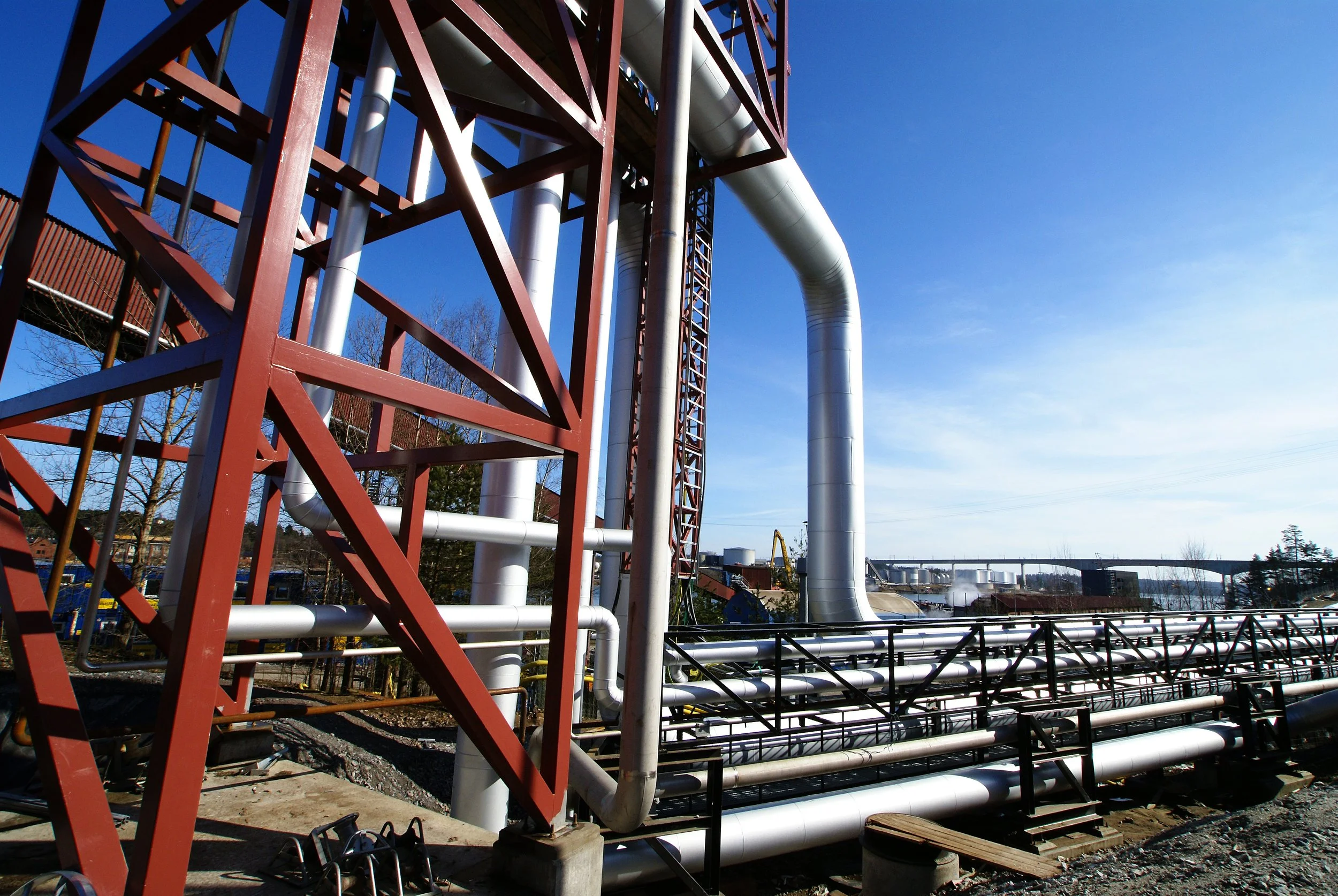 Estructura industrial con tuberías y tren de transmisión en un día soleado con cielo despejado.