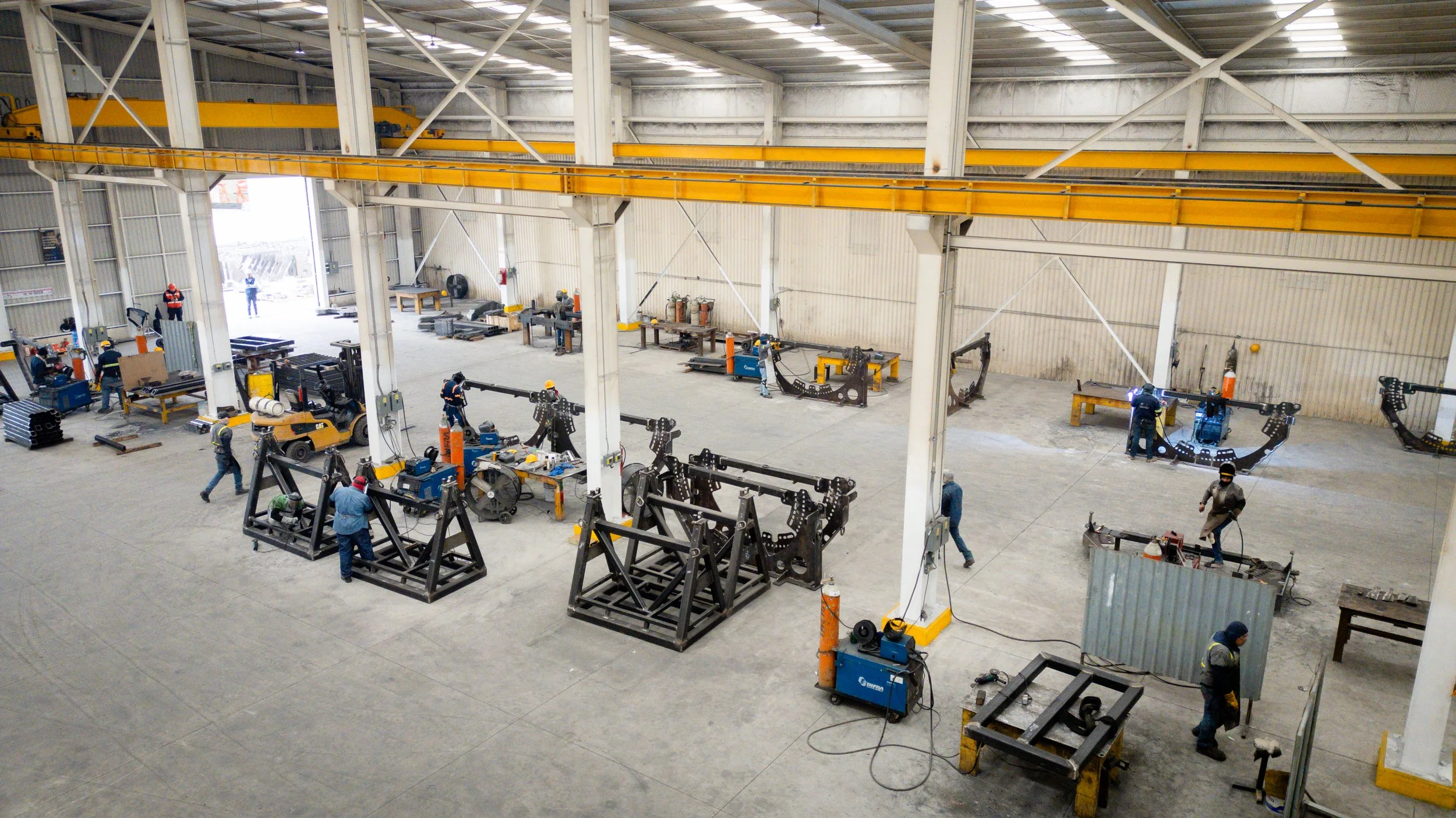 Interior de un almacén industrial con varias máquinas y trabajadores realizando tareas de fabricación.