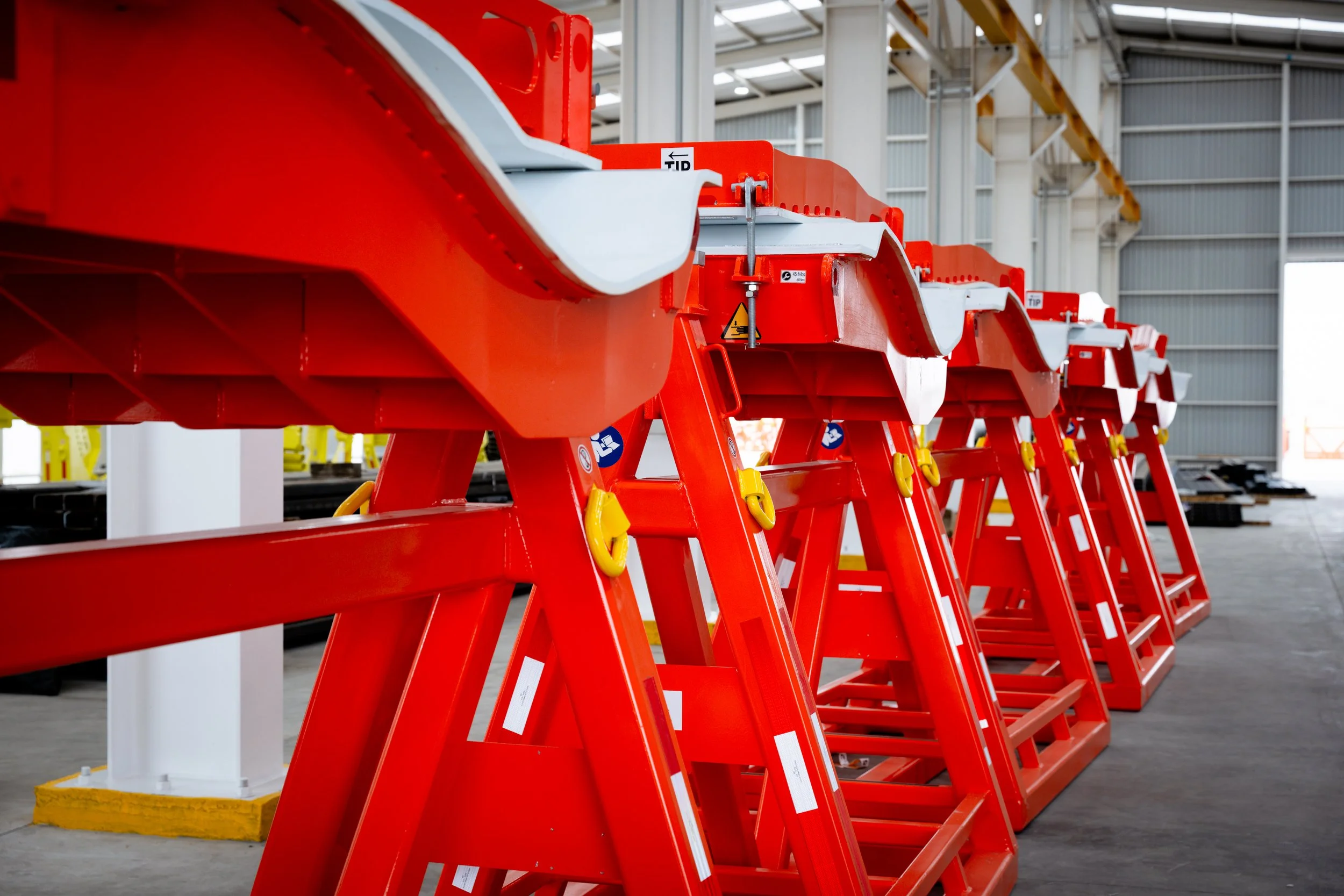 Escaleras rojas en un almacén industrial, apiladas en línea, en un ambiente amplio con paredes de metal y techo de cristal
