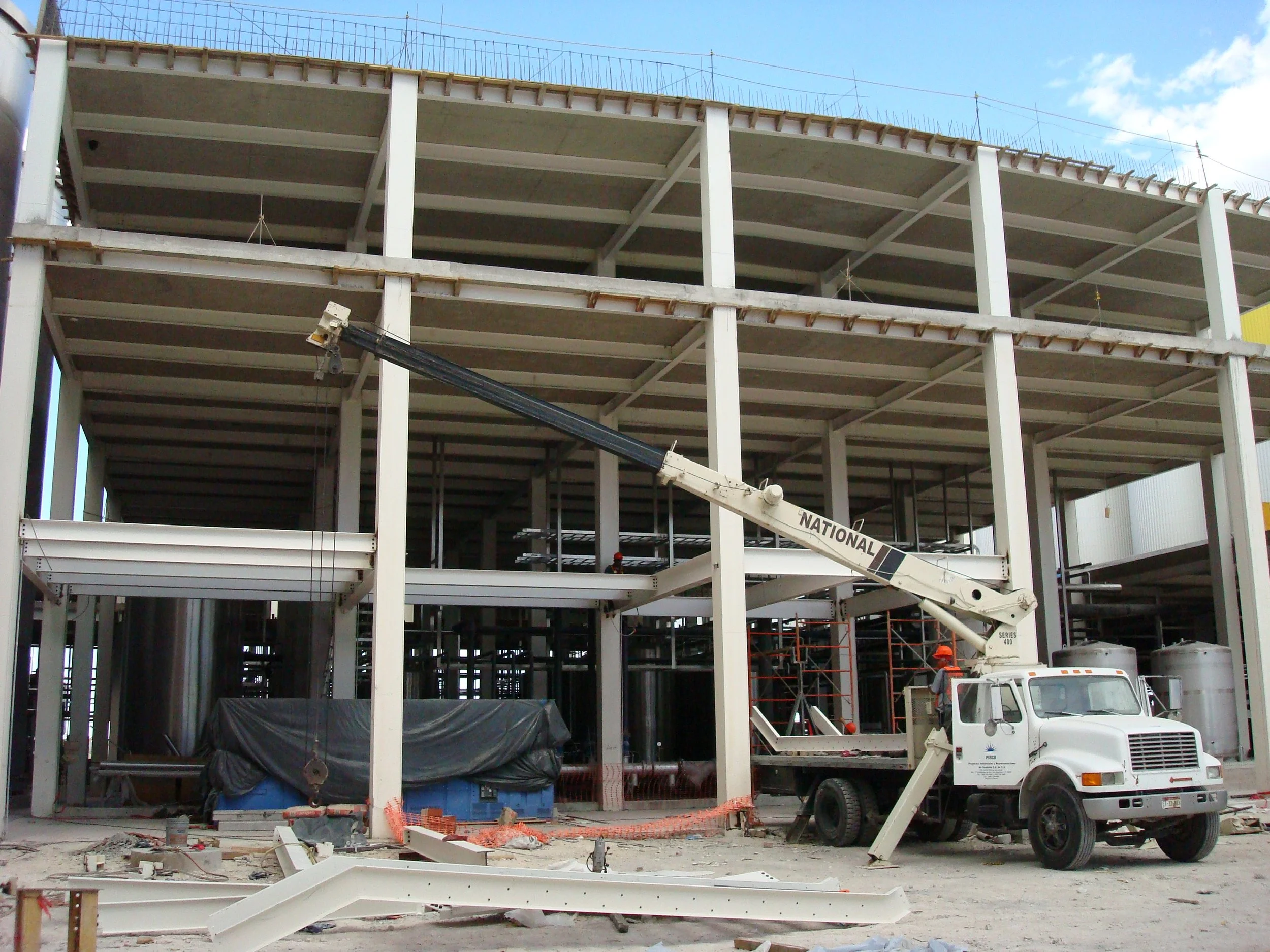 Construcción de un edificio de varios pisos en progreso, con una grúa y trabajadores en la obra.