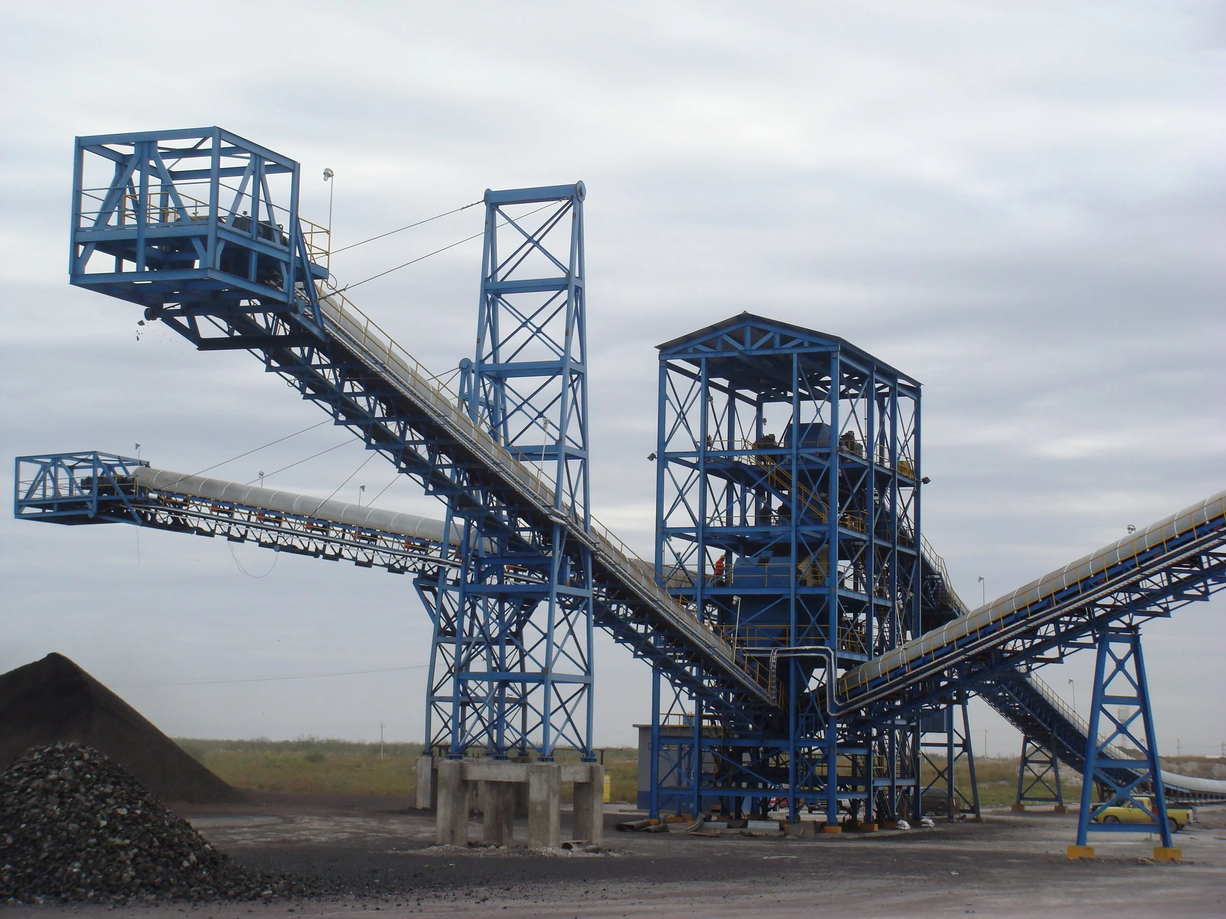 Estructura metálica de una planta industrial, posiblemente una planta de procesamiento o minería, con plataformas y tuberías de color azul y una tubería grande en la parte inferior.