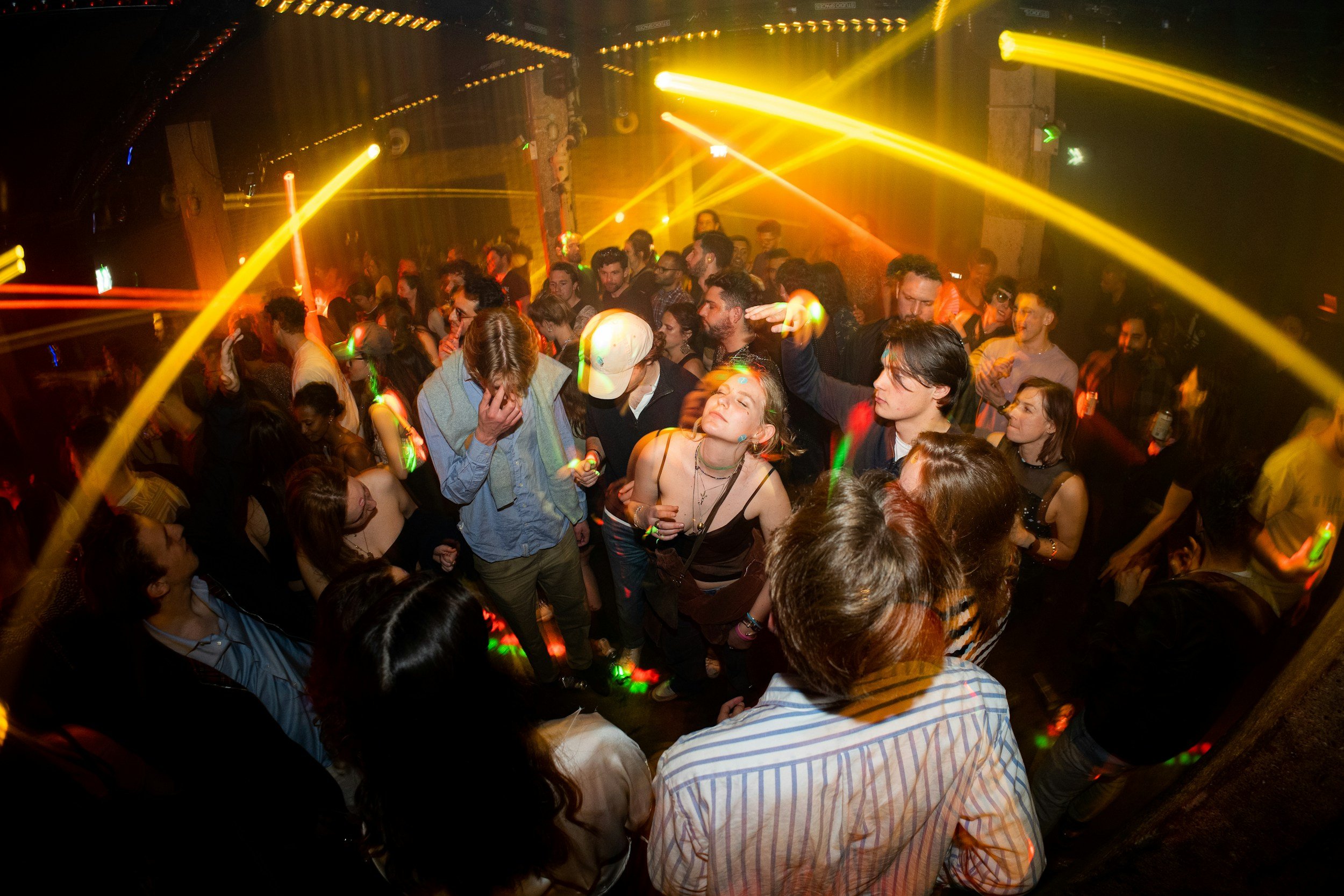 A large group of people dancing in a club with decorative lens flares and distortion