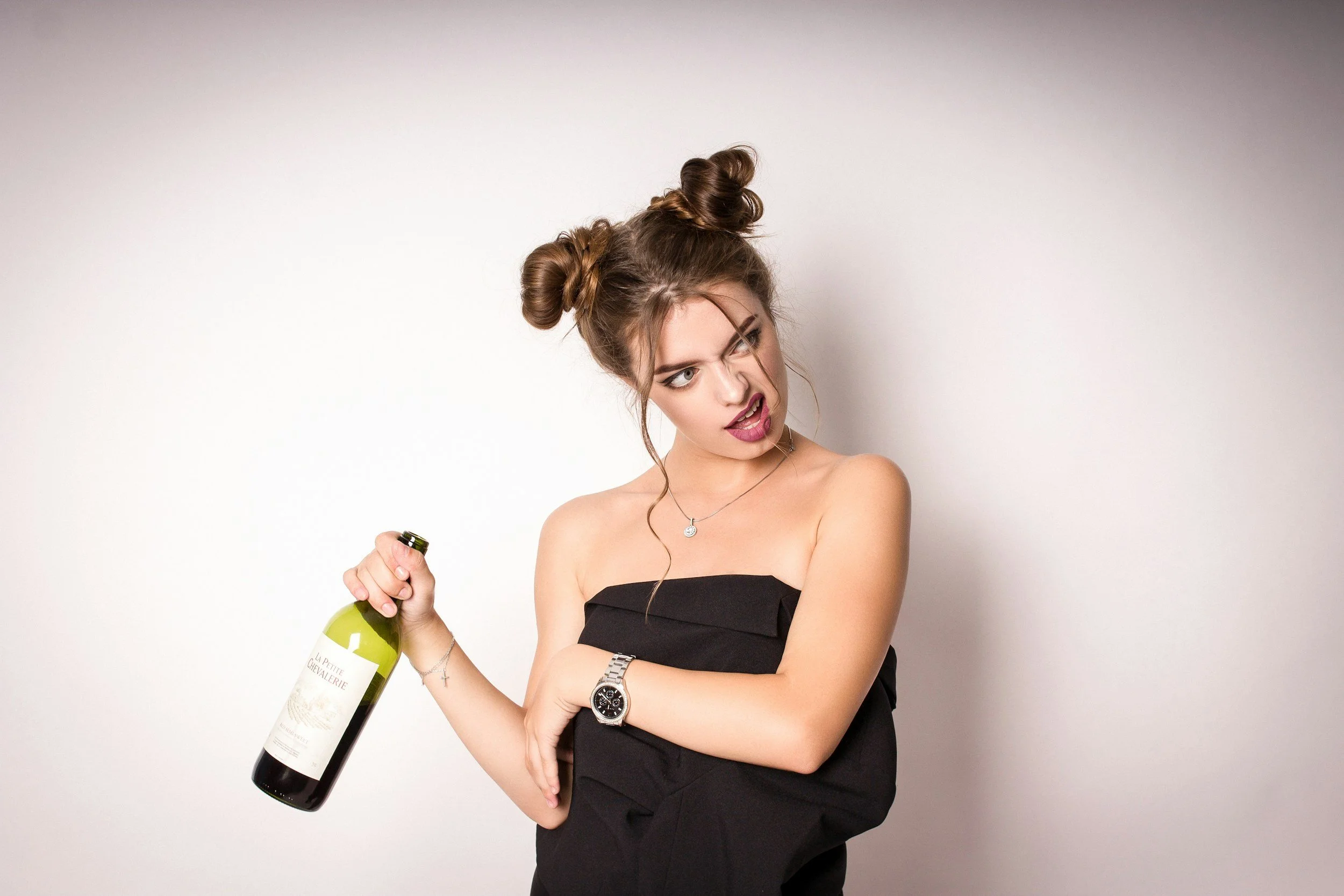 Woman with wild hair holding wine bottle and making an incredulous face.