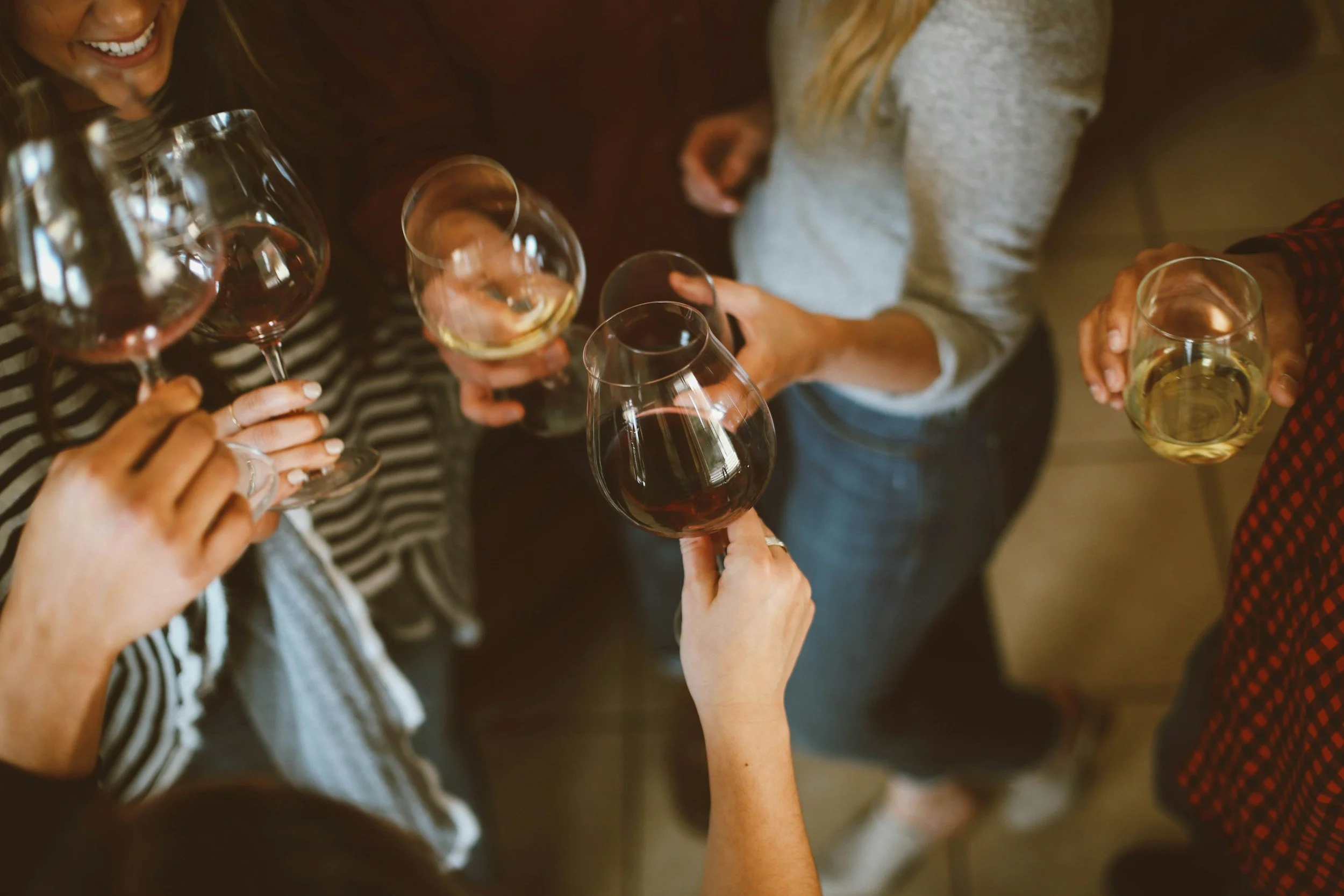 Group of people holding wine glasses and clinking them.  One glass of wine should not be enough to get you drunk.
