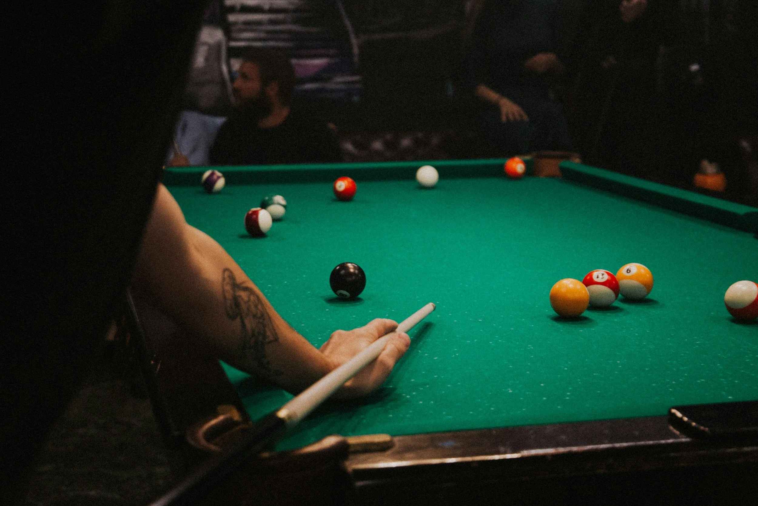 A man with a pool cue lining up his shots.  Physical activity can help you drink less and feel more coordinated while you drink.