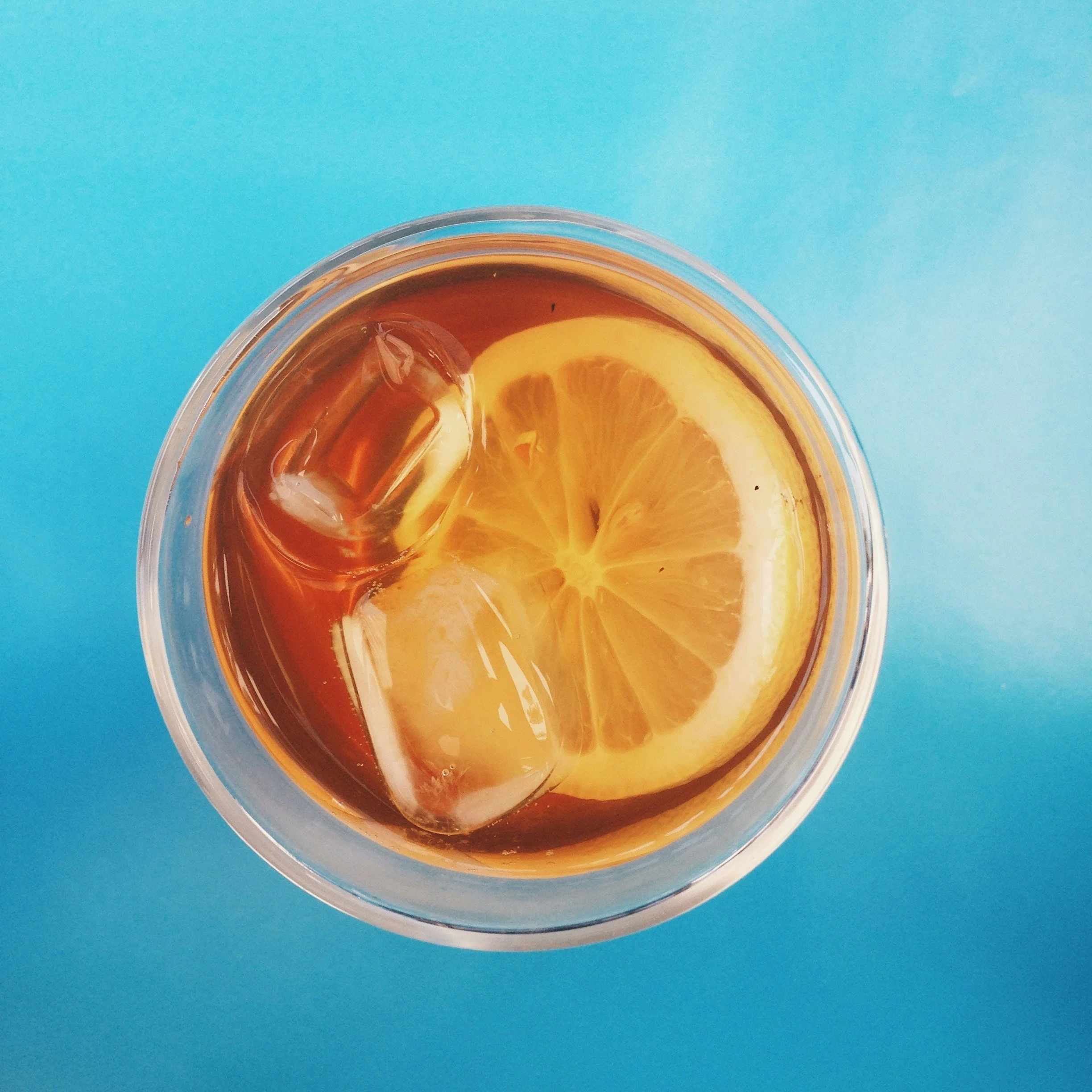 Close up of the top of a glass of Long Island Iced tea with a lemon in it