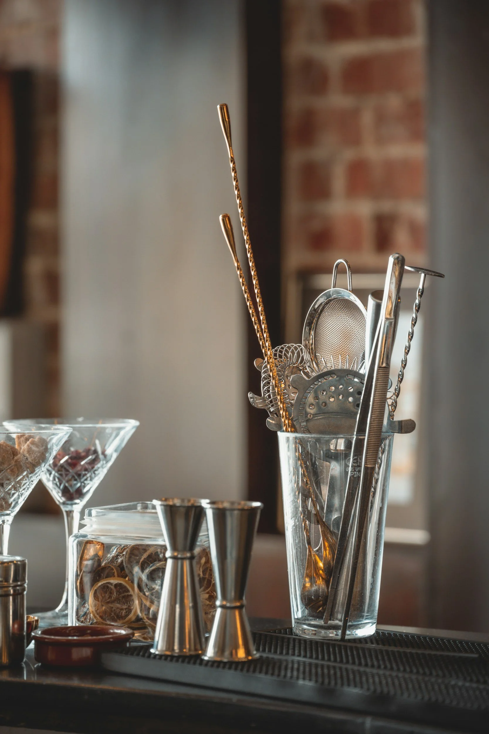 A jar containing multiple strainers and bar spoons