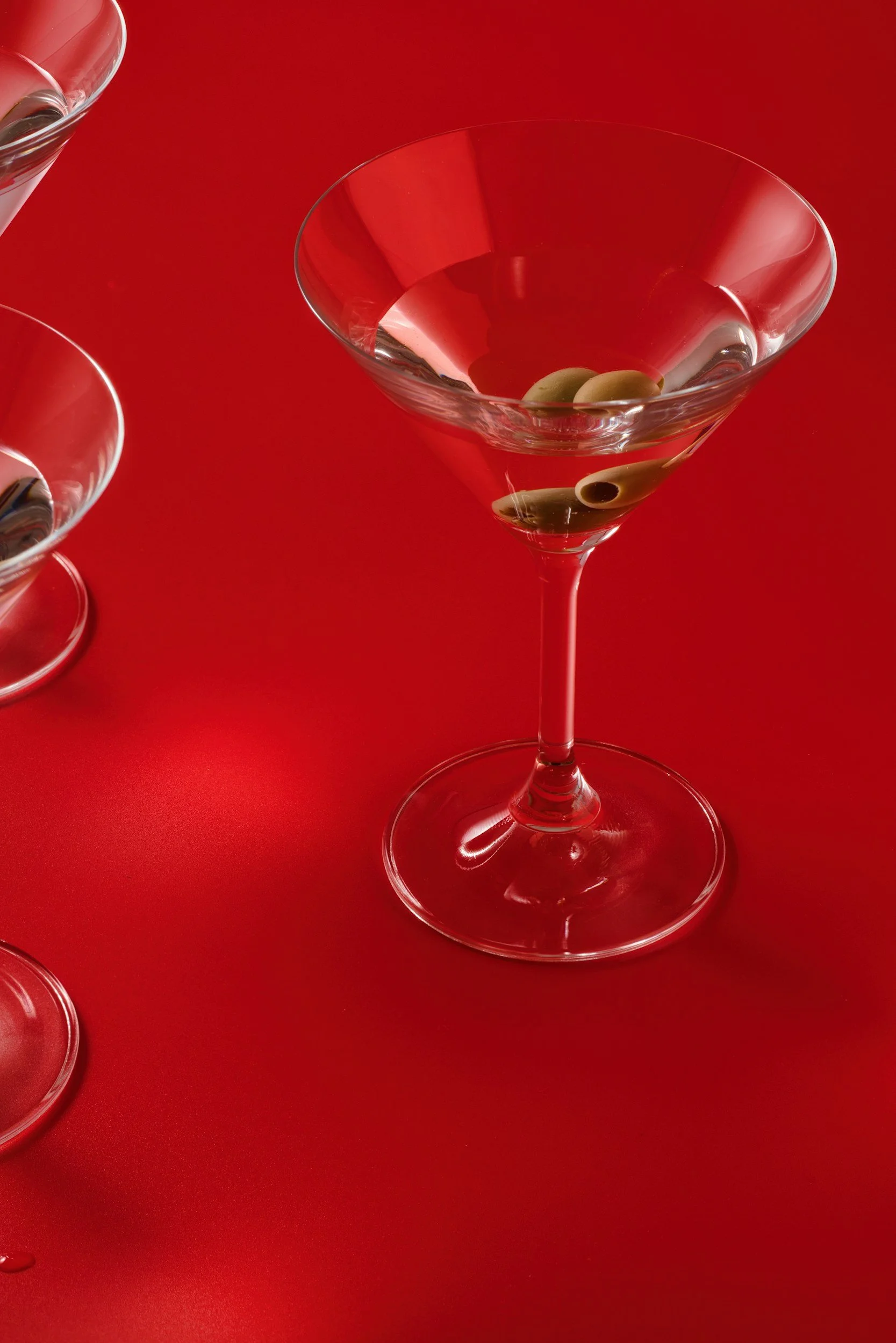 Martini glass with olives, on a cherry red background