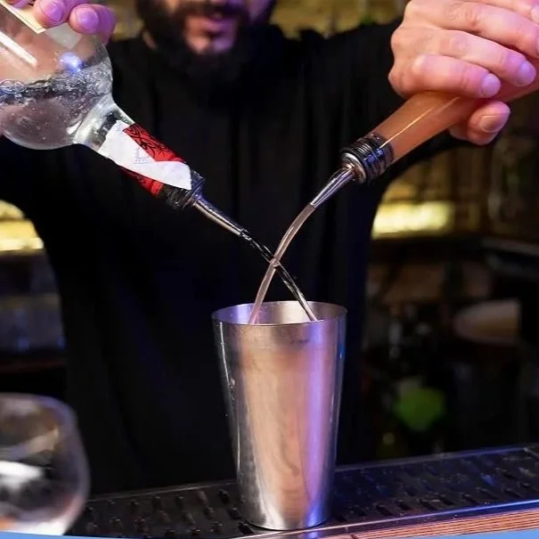 Bartender pouring two bottles at once into a tin using pour spouts