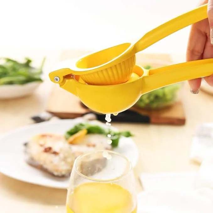 A yellow lemon juicer with a lemon pressed between two halves.  By using the handles to create pressure, juice is pushed out of holes in the bottom of the cup.