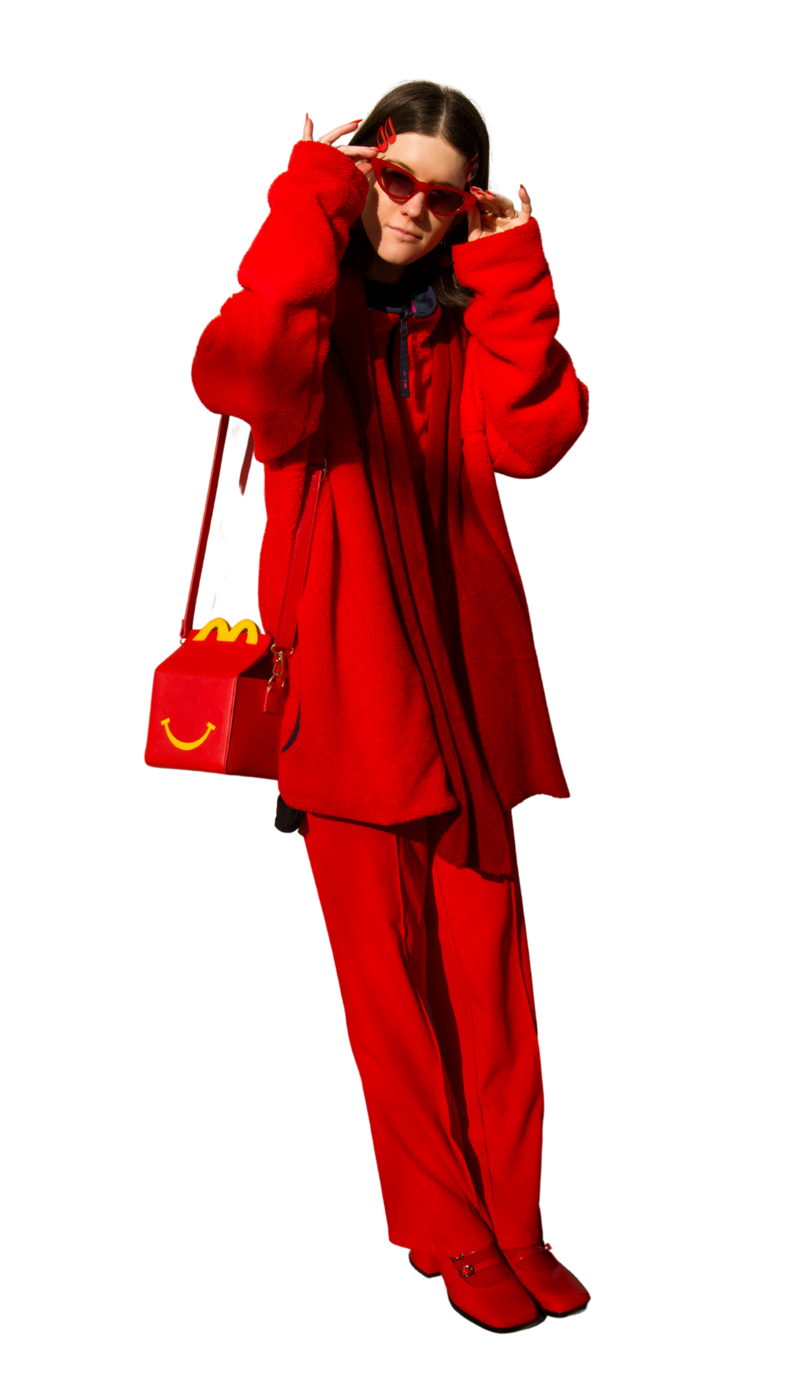 A woman wearing red sunglasses, a red fleece jacket, red pants, and red shoes, holds her glasses with both hands. She carries a red bag with a yellow smiley face and McDonald's logo. The background is digital glitch and black.