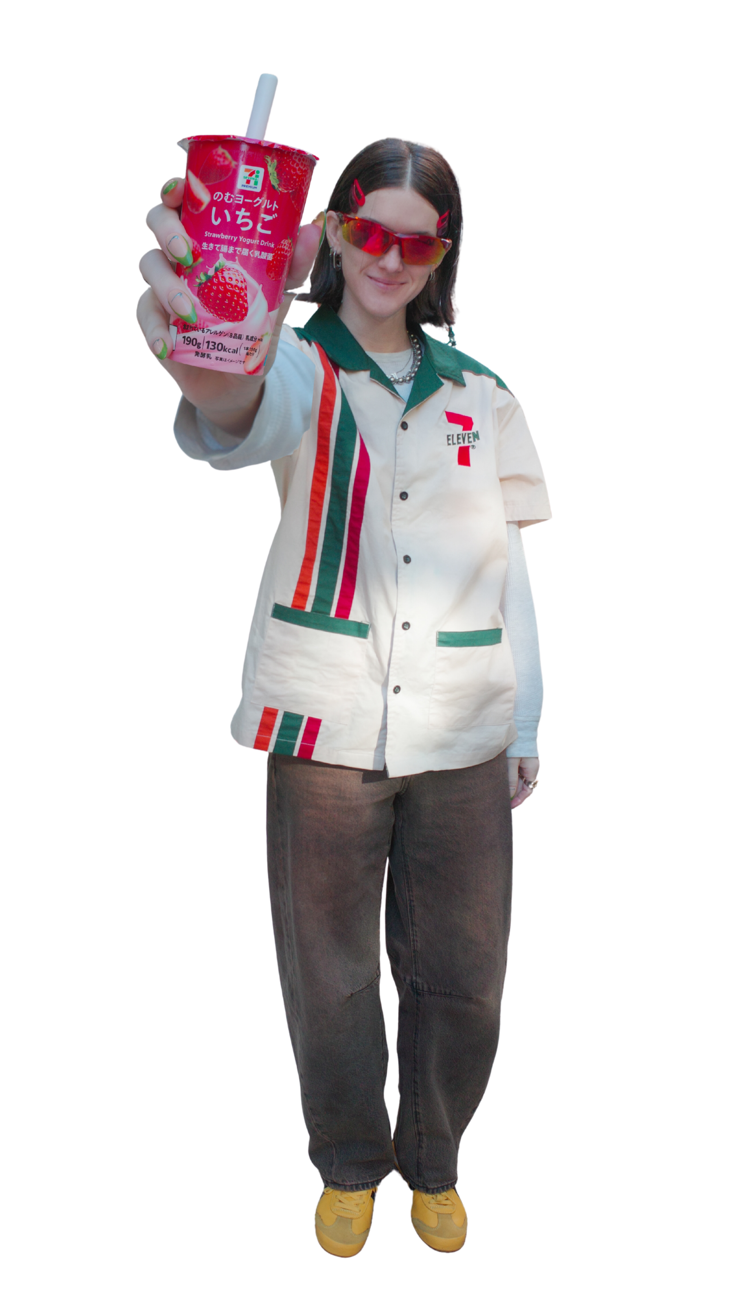 A person dressed in a retro-style 7-Eleven uniform holding a strawberry yogurt drink, wearing sunglasses and yellow sneakers.