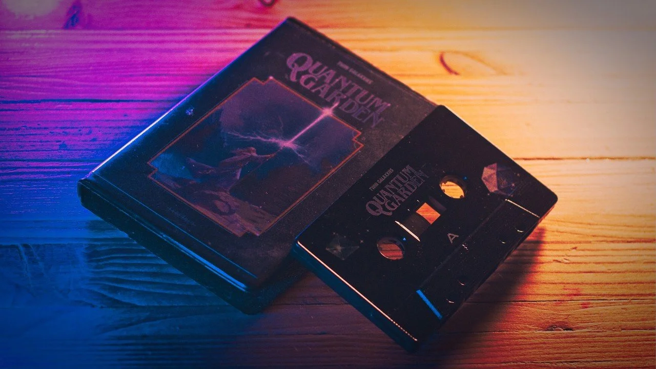 Close-up of a cassette tape copy of Quantum Garden by Twin Galaxxies, lit in orange and purple.