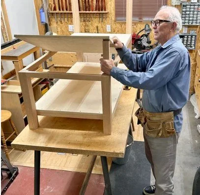 Volunteer builder constructing a custom wooden child's bed in the Ability Workshop