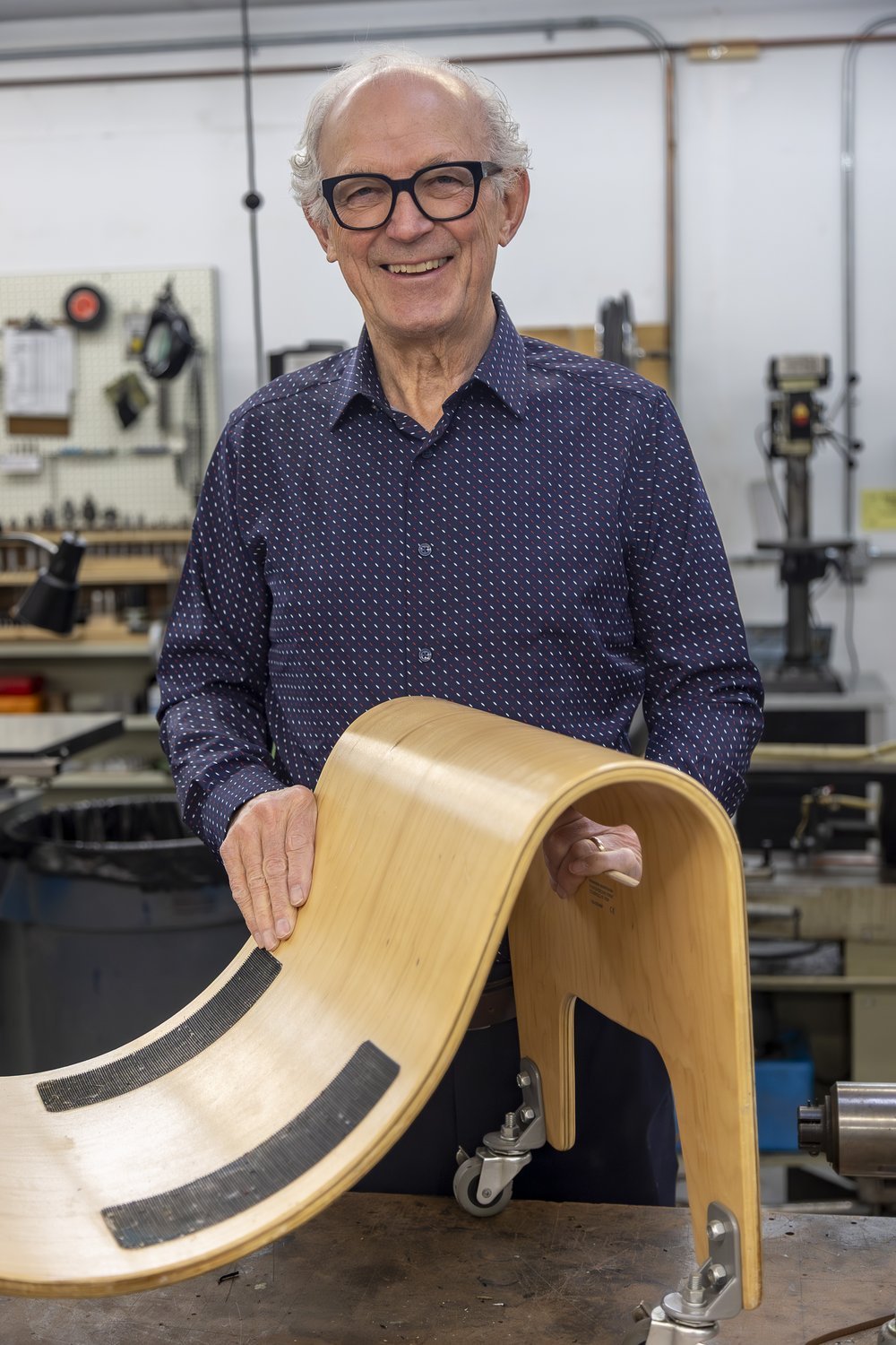 Ed Marchand, Ability Workshop board member, holding a curved wooden rocker ramp in the workshop