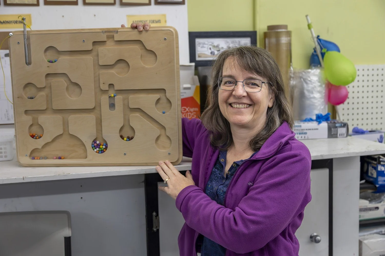 Renee Watson, Ability Workshop board member, with a custom wooden marble maze sensory board