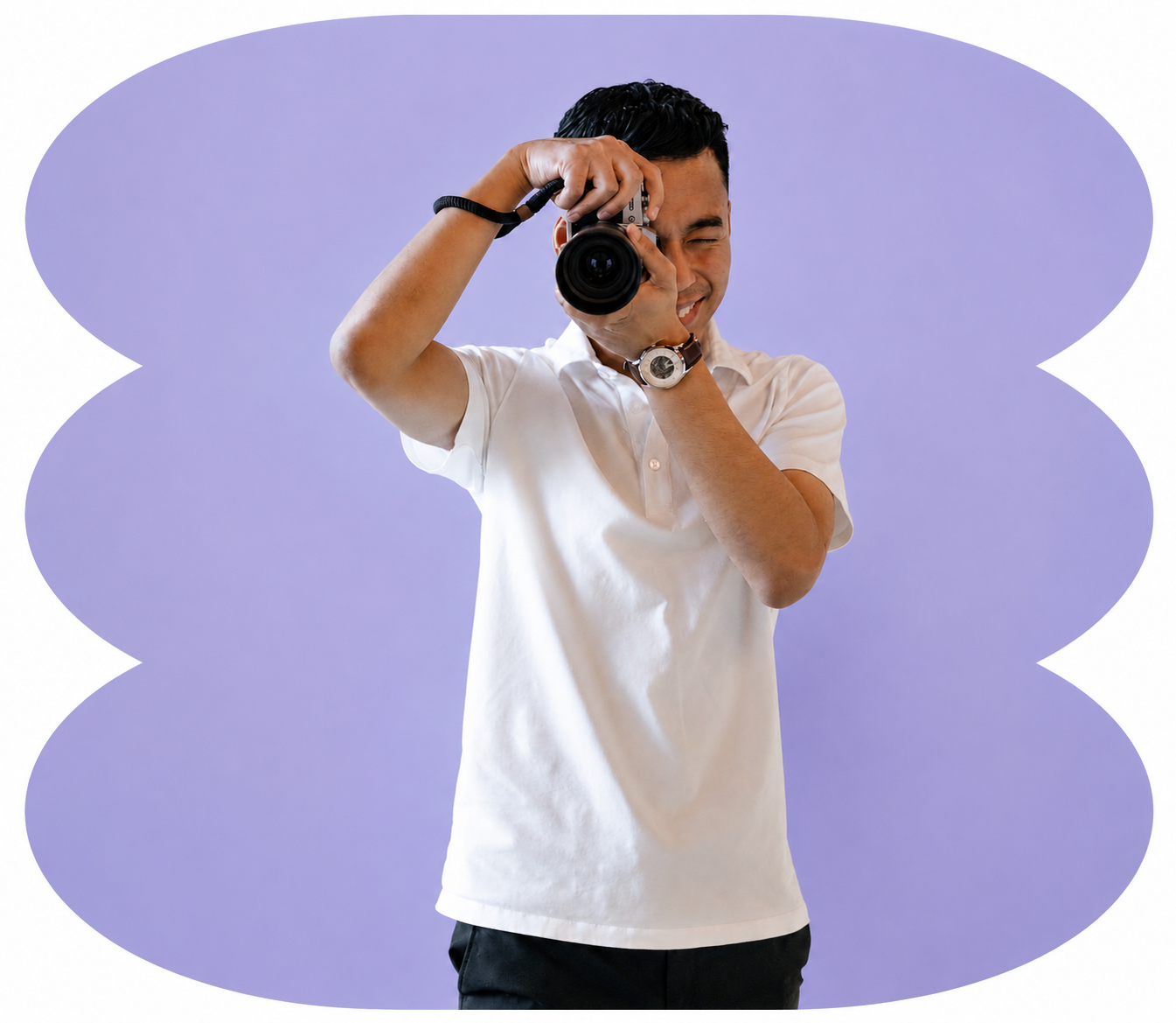A young man taking a photograph with a camera. He is smiling and wearing a white short-sleeved shirt and a wristwatch. The background is a purple gradient with a decorative scalloped border.