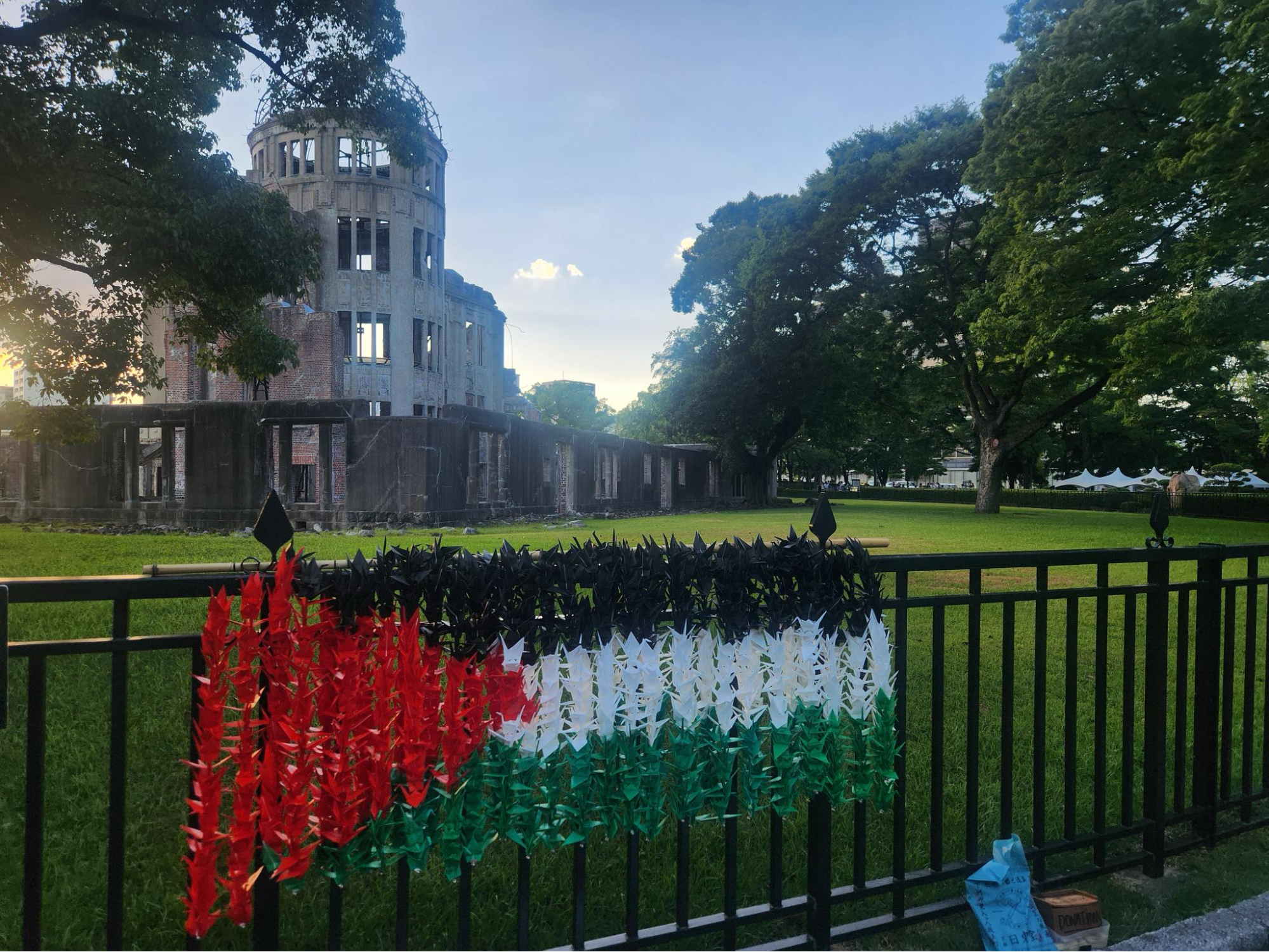 The Hiroshima Atomic Bomb dome with a Palestinian flag banner made of paper cranes. August 2026