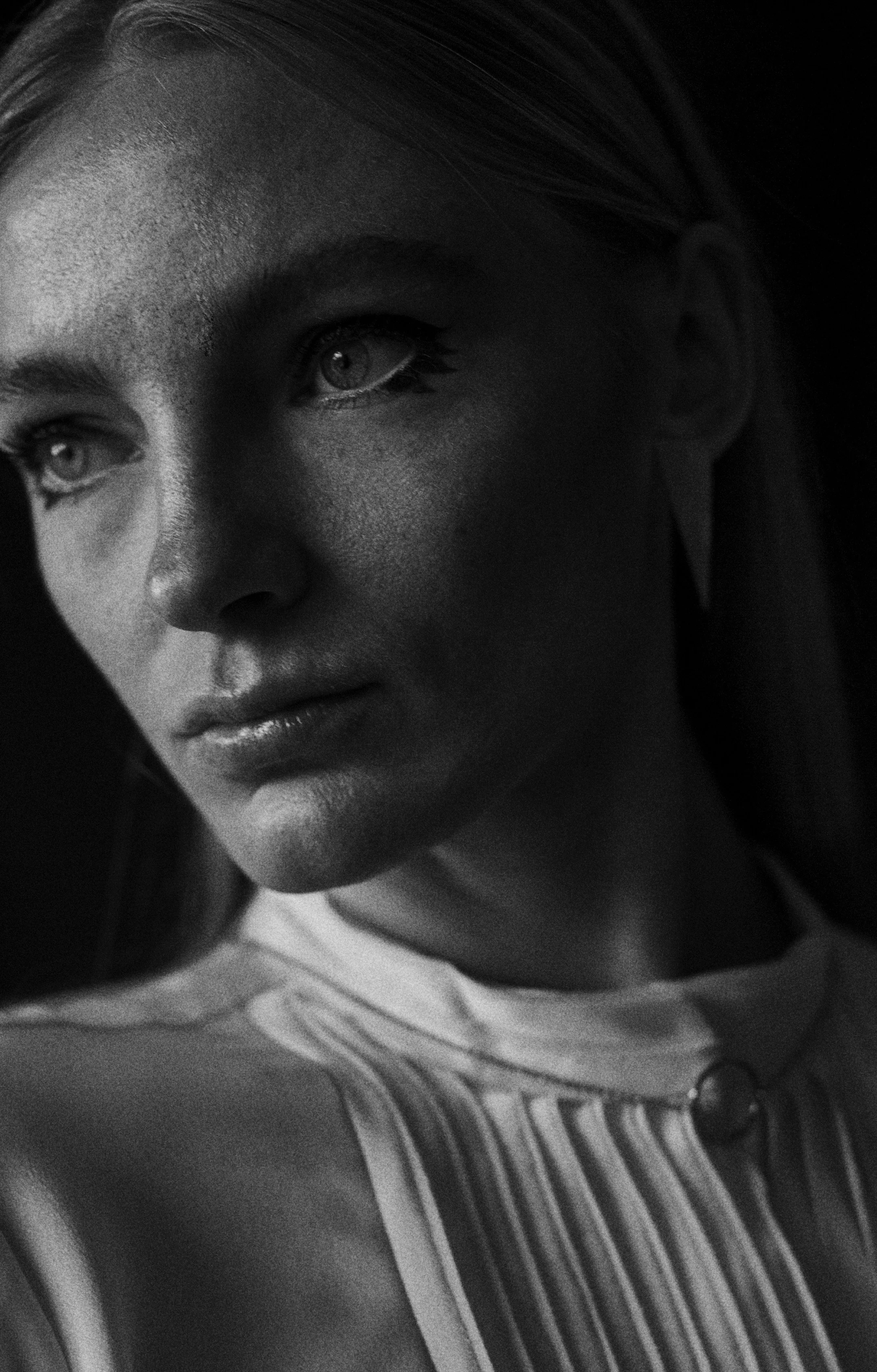 Retrato en blanco y negro de una mujer con cabello largo y ropa de rayas, mostrando solo la parte superior de su rostro y hombros.