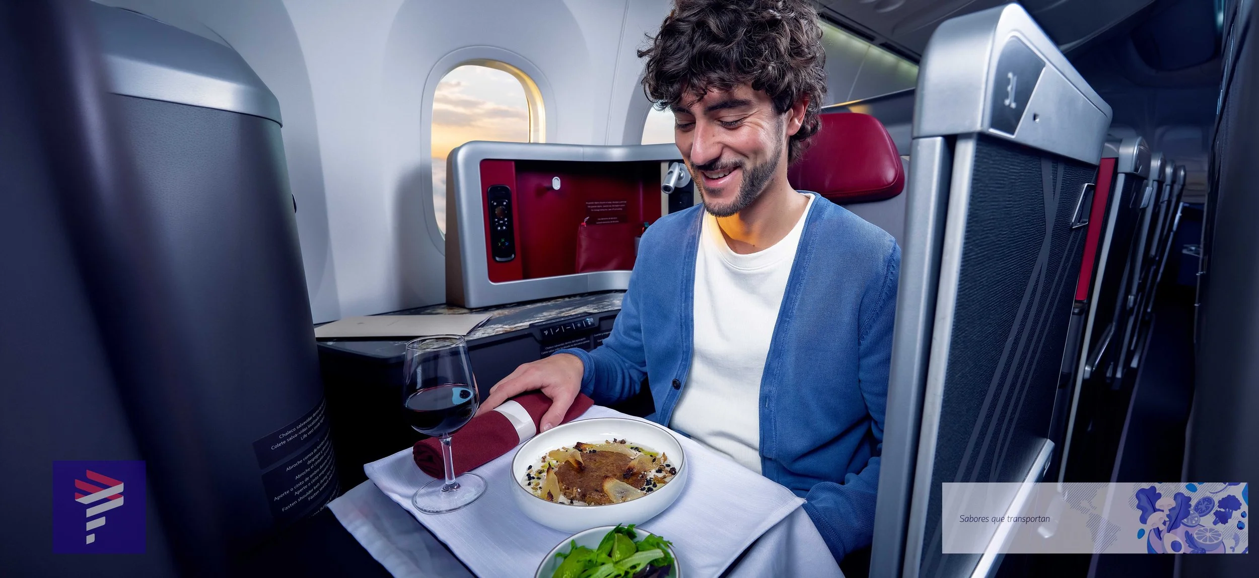 Hombre en clase de avión disfrutando comida y vino.