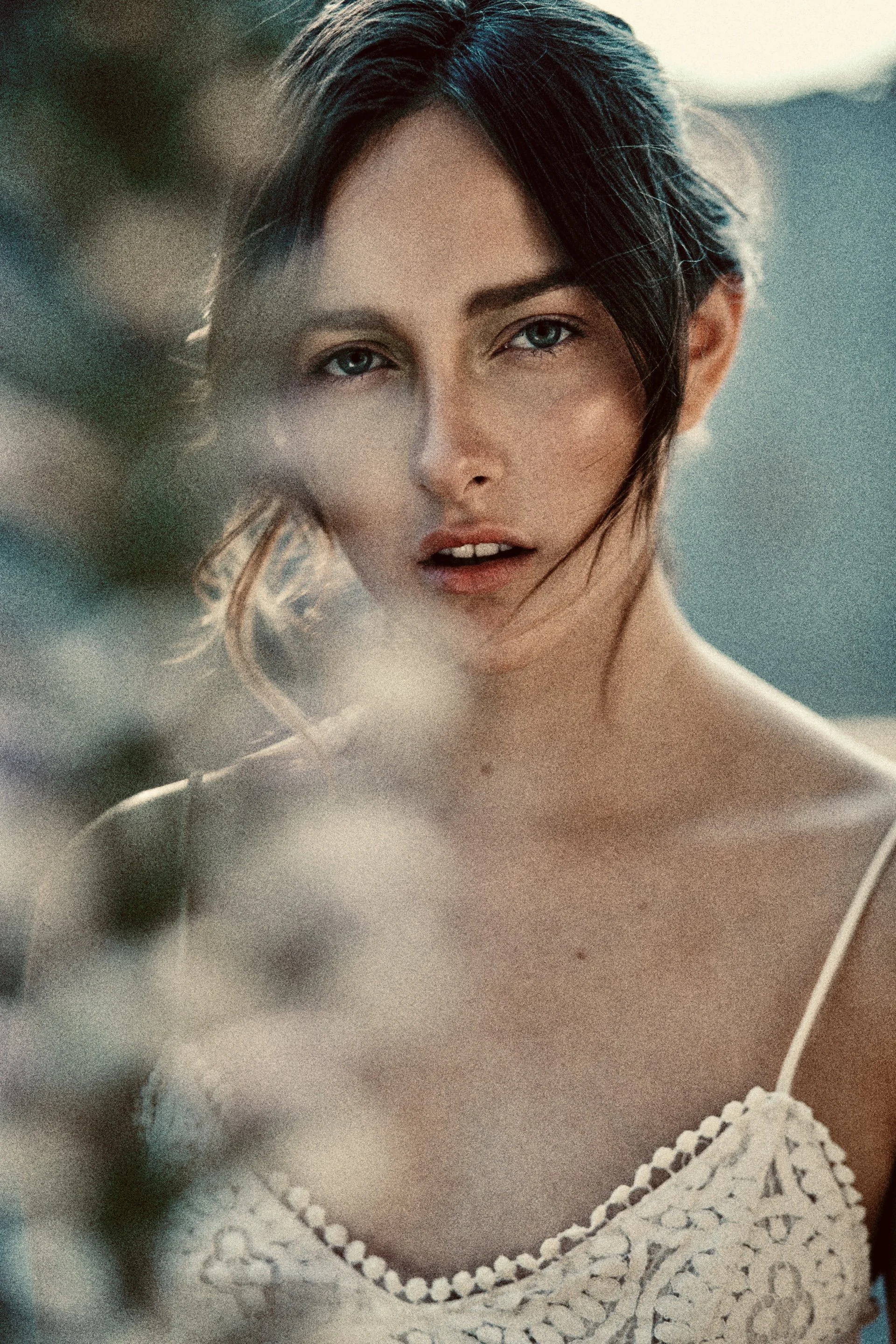 Retrato de una mujer con cabello corto y ojos claros, vestida con un top de crochet blanco.