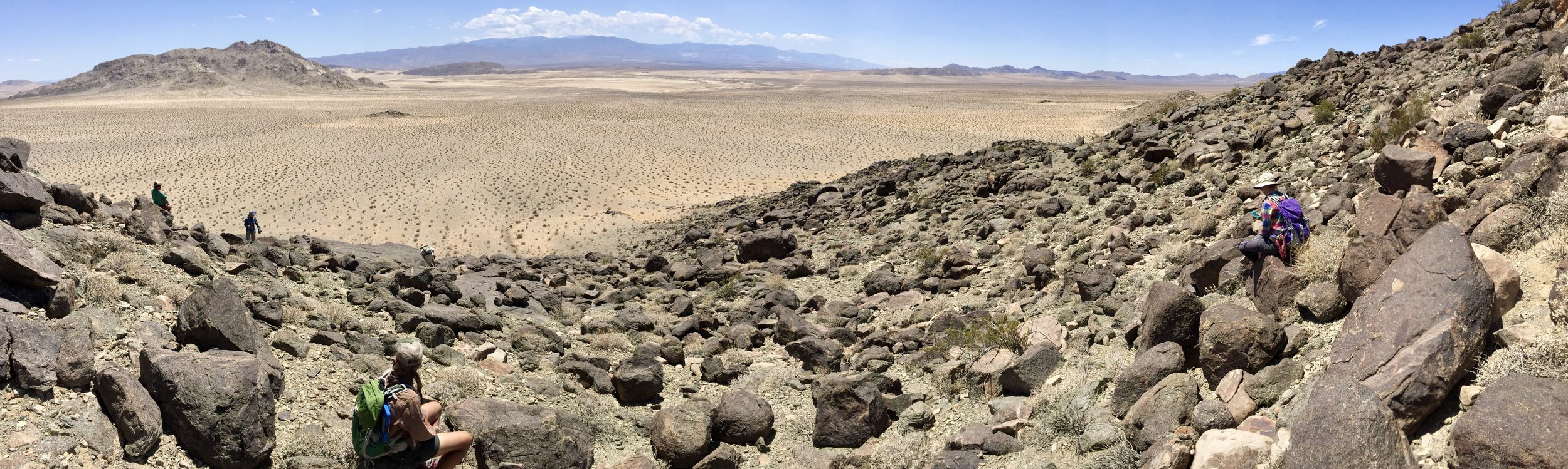 Wildlife survey crew stopped for rest on rocky desert slope high above lowlands - Wilder Ecological