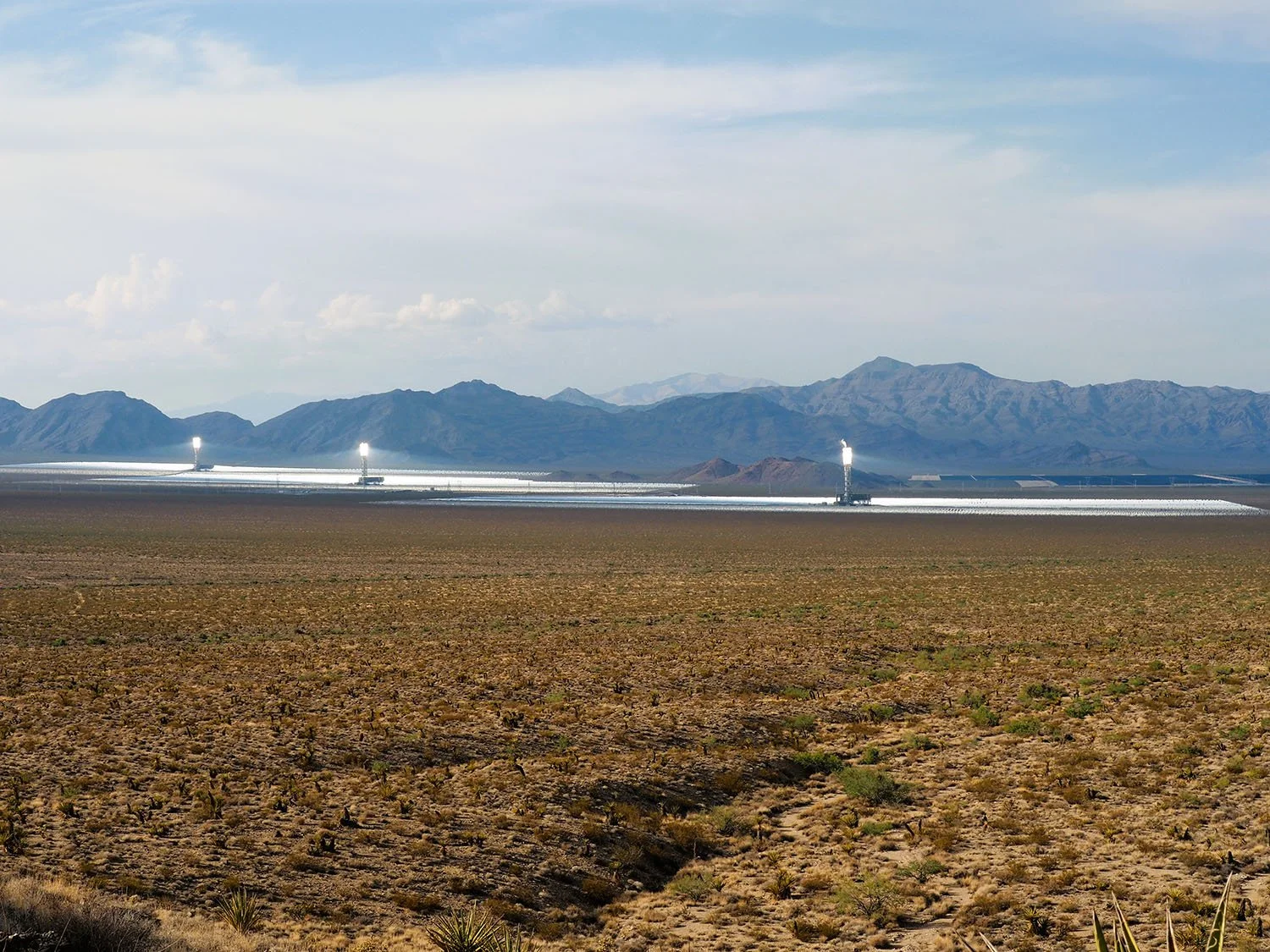 A desert landscape with solar farms and mountains in the background.