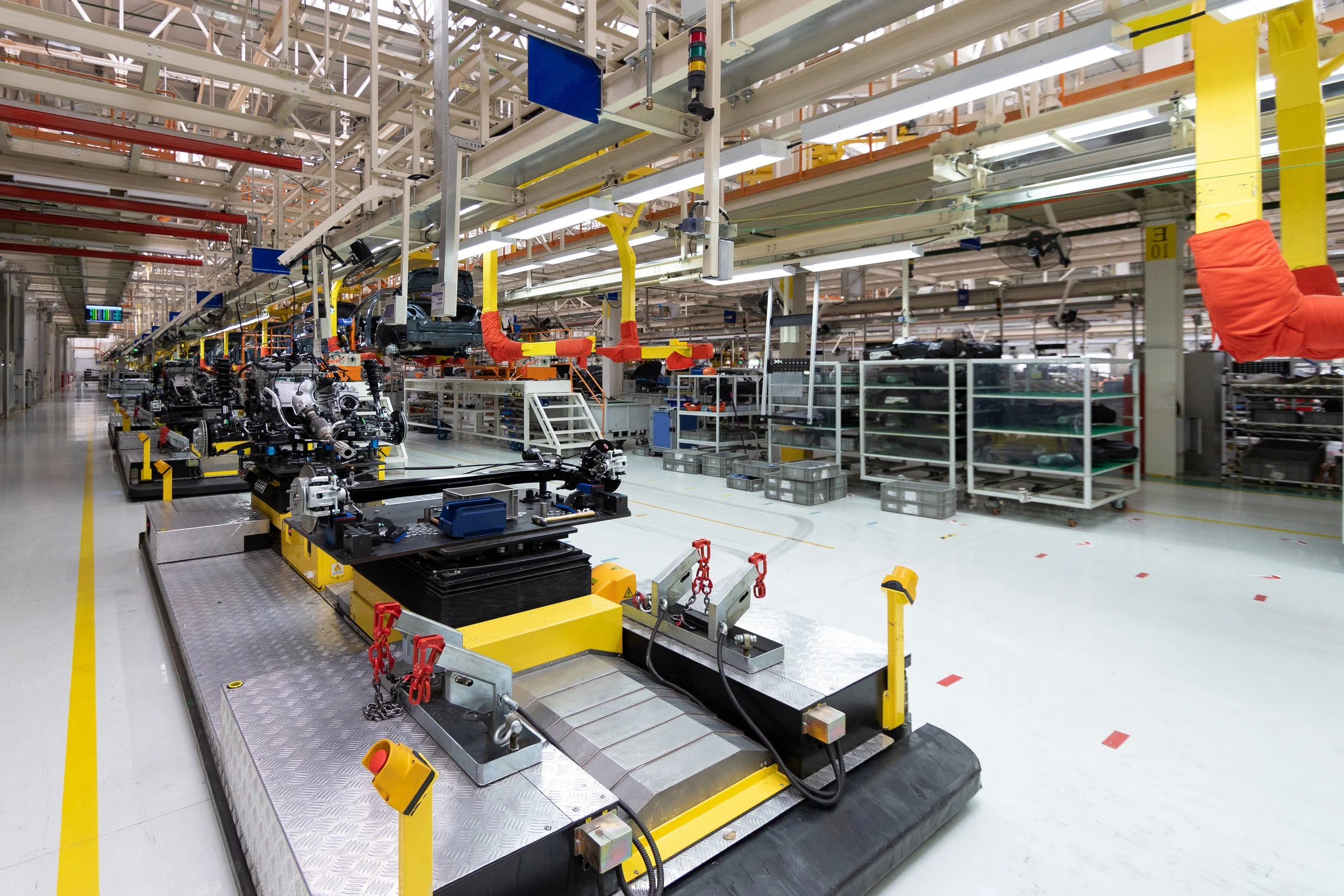 Inside an automotive manufacturing plant with assembly lines and robotic equipment working on car frames.