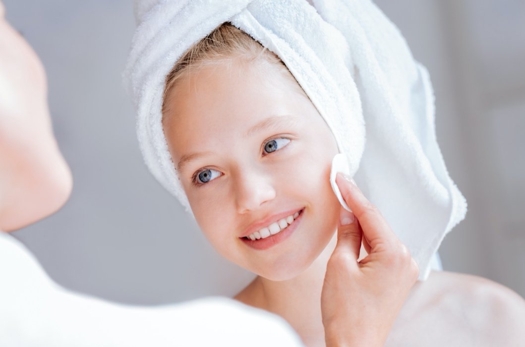 Young girl with a towel wrapped around her head smiling while her mom is applying product from her fundraiser.
