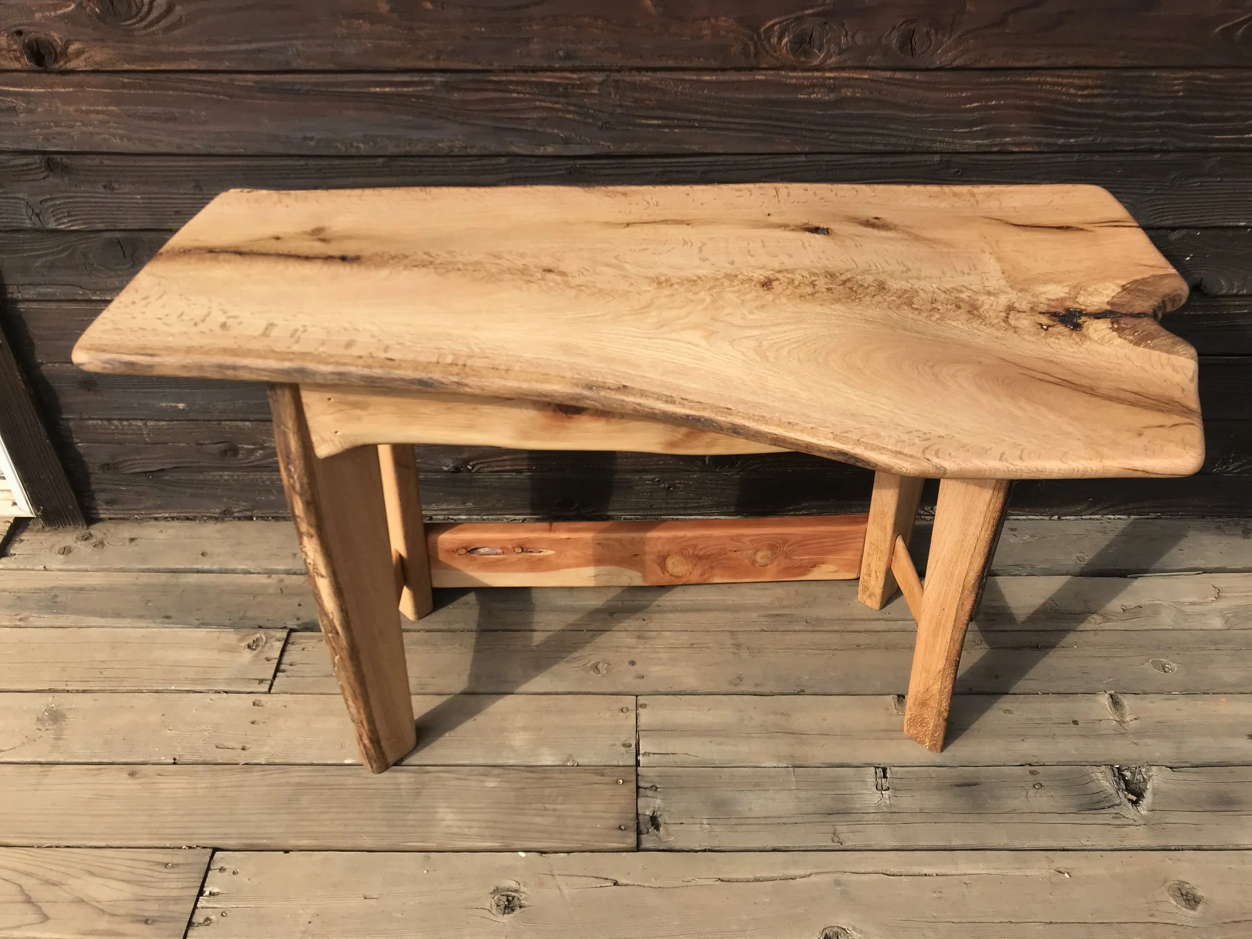 A wooden bench placed on a rustic wooden deck.