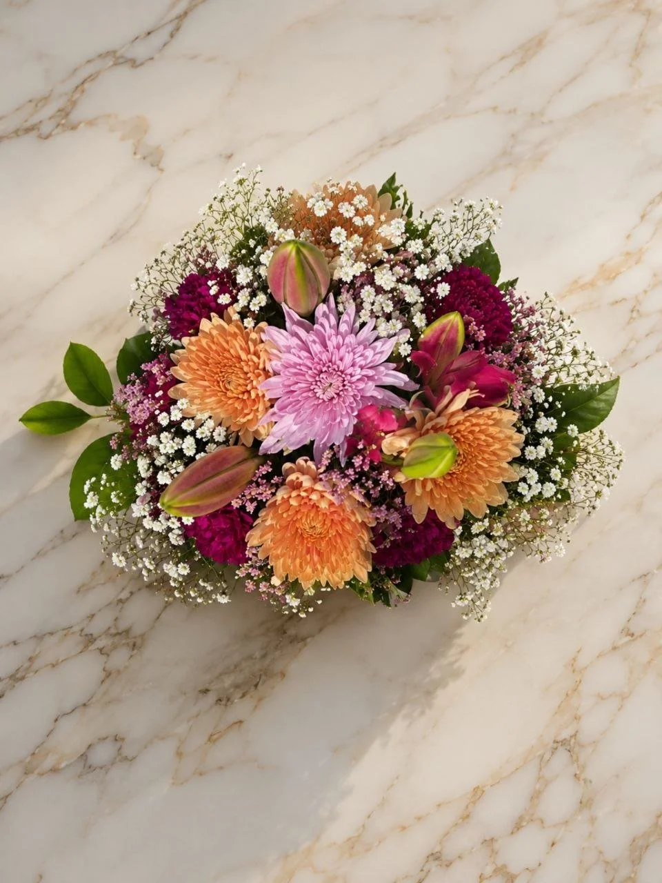 Colorful bouquet of various flowers including pink, orange, purple, and white blossoms on a white marble surface.