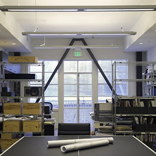 Bookshelves and equipment in a modern office or studio space with large windows and an exit sign.