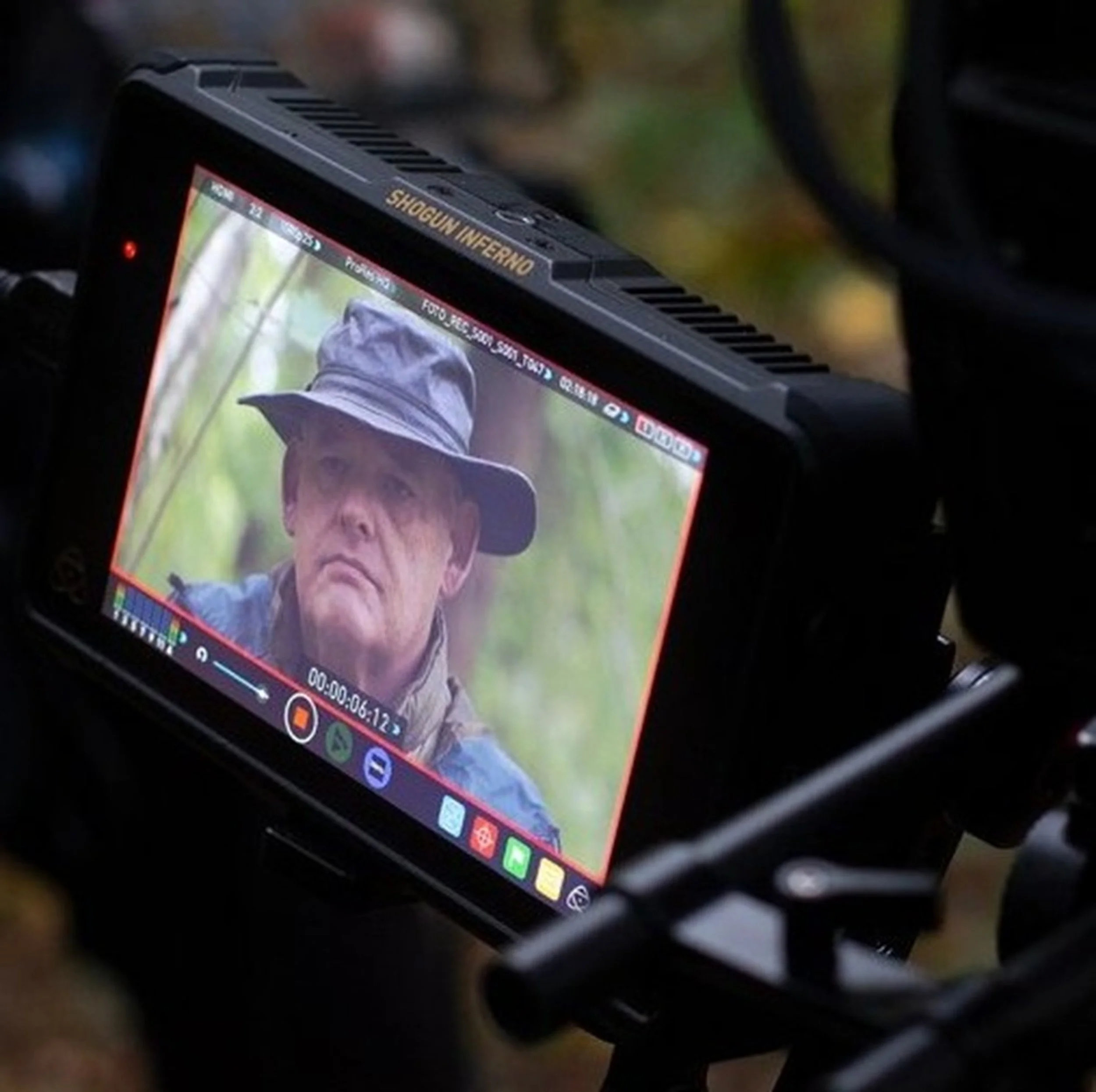 Close-up of a smartphone displaying a photo of an elderly man, with a caption that reads "SHOGUN INFERNO" on the top edge of the device.